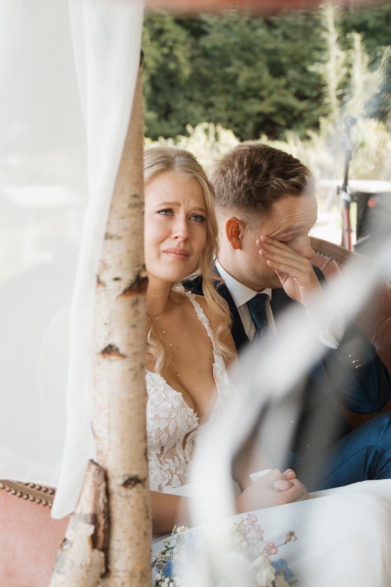 Ein Brautpaar sitzt bei einer emotionalen Zeremonie, die Braut schaut emotional.