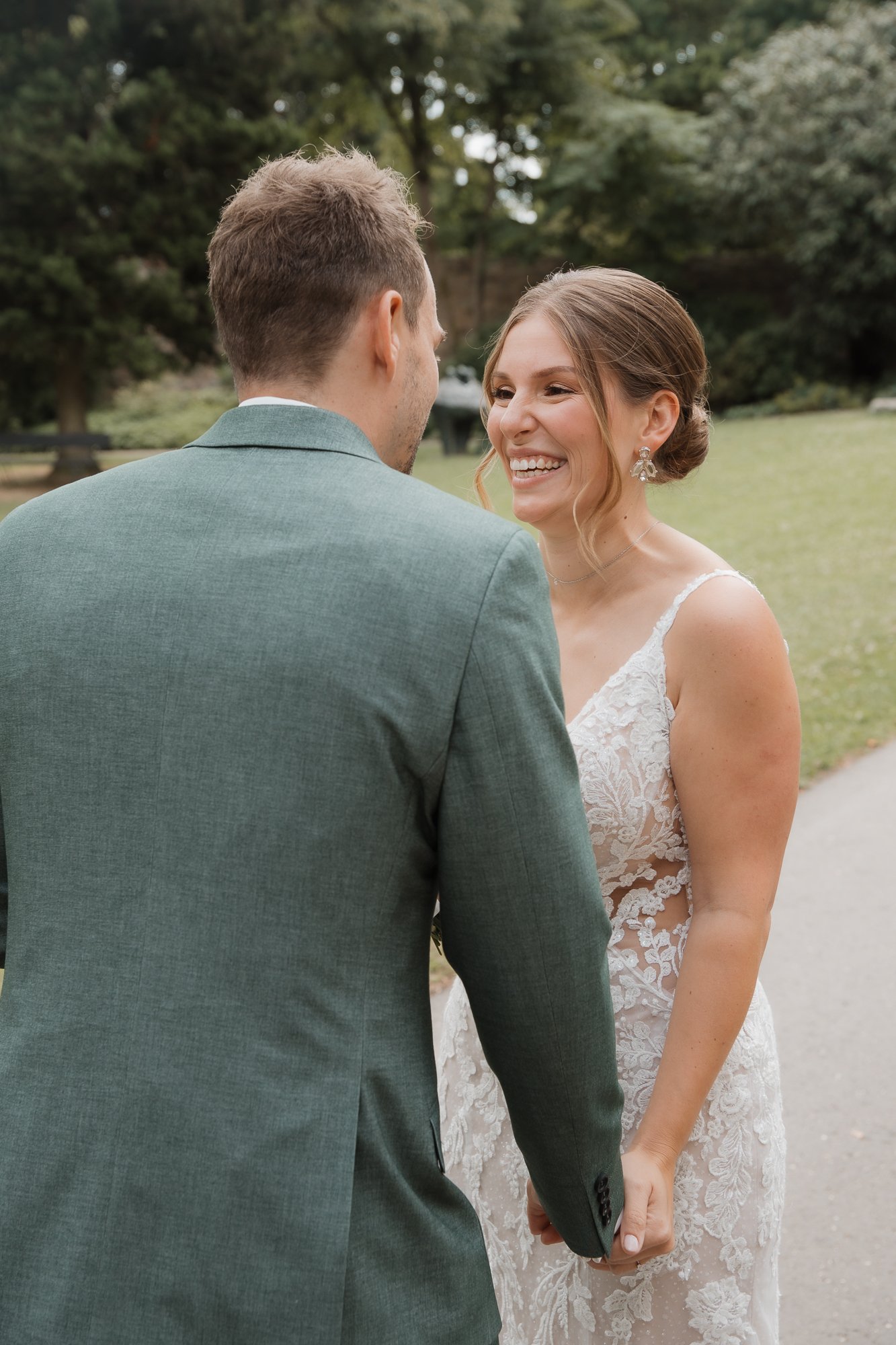 Ein Brautpaar hält Händchen im Freien, die Frau lächelt glücklich.
