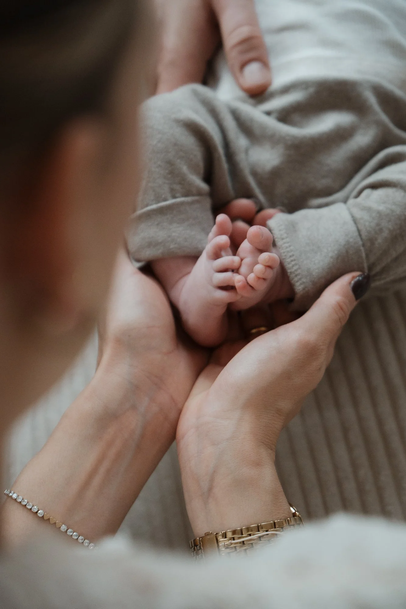 Nahaufnahme von einer Person, die ein neugeborenes Baby hält, focusing auf die winzigen Füße des Babys.