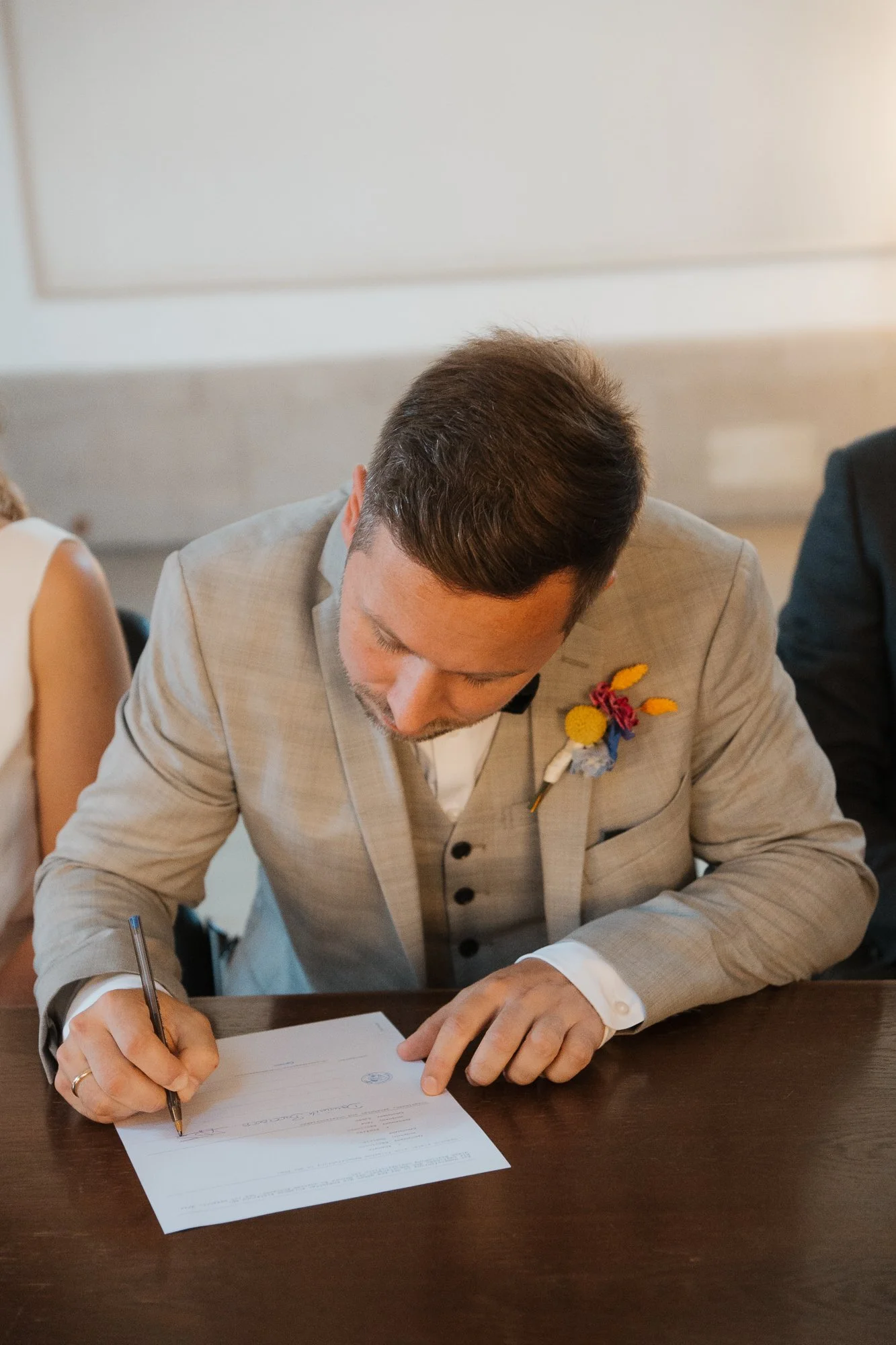 Mann in Brautanzug unterschreibt Dokument bei einer Hochzeit