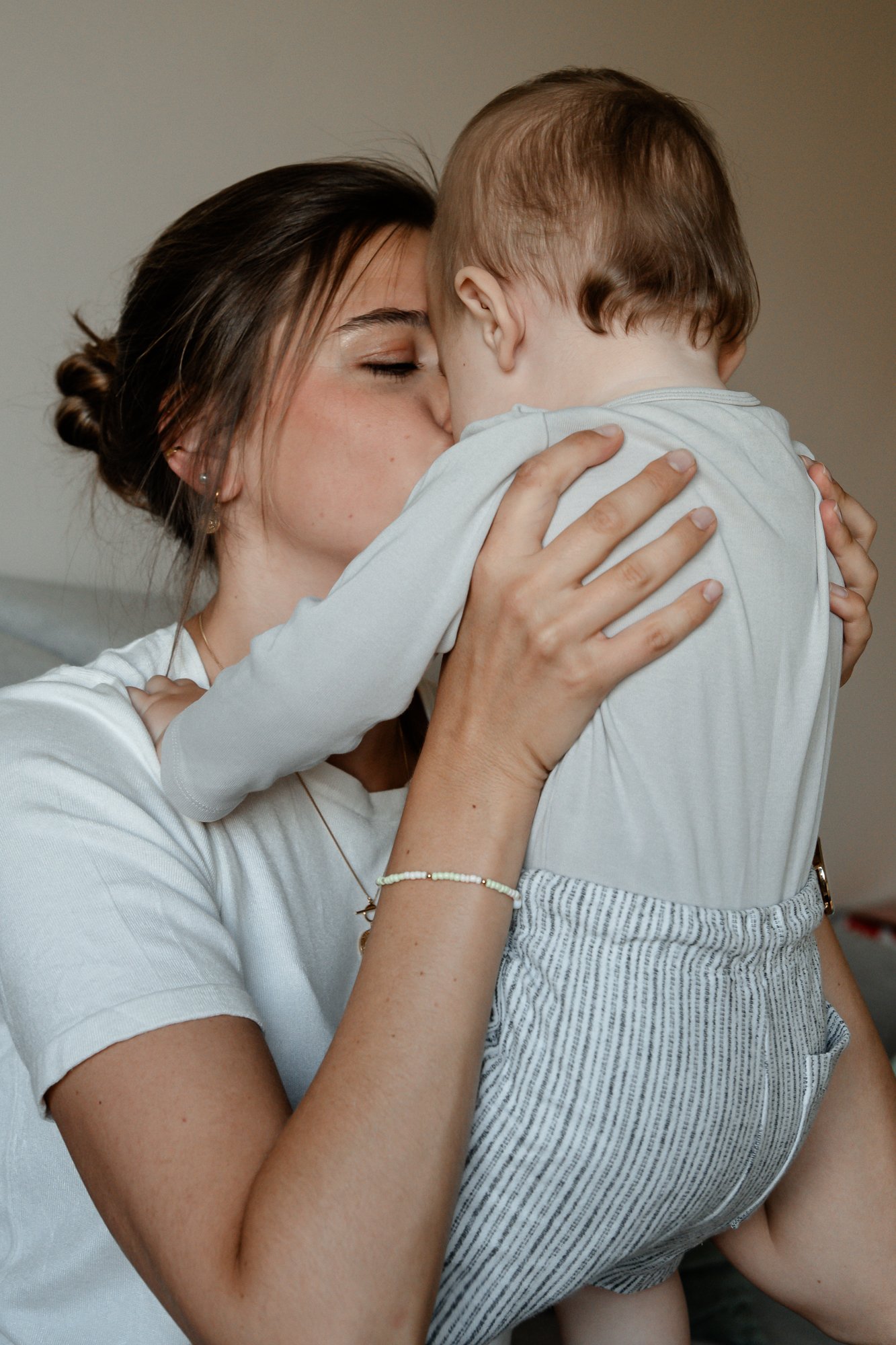 Eine Frau hält ein Kind beim Kuscheln und küsst es auf die Wange.