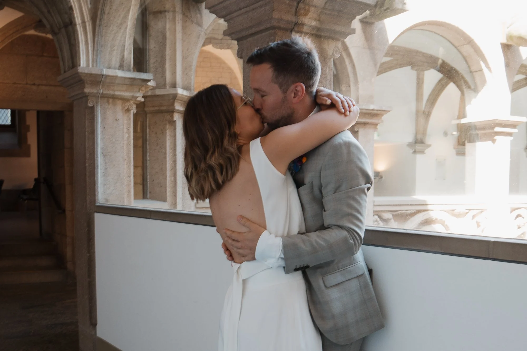 Ein Paar küsst sich innig, während sie sich umarmen, in einer historischen Kirche mit gotischen Bögen im Hintergrund.