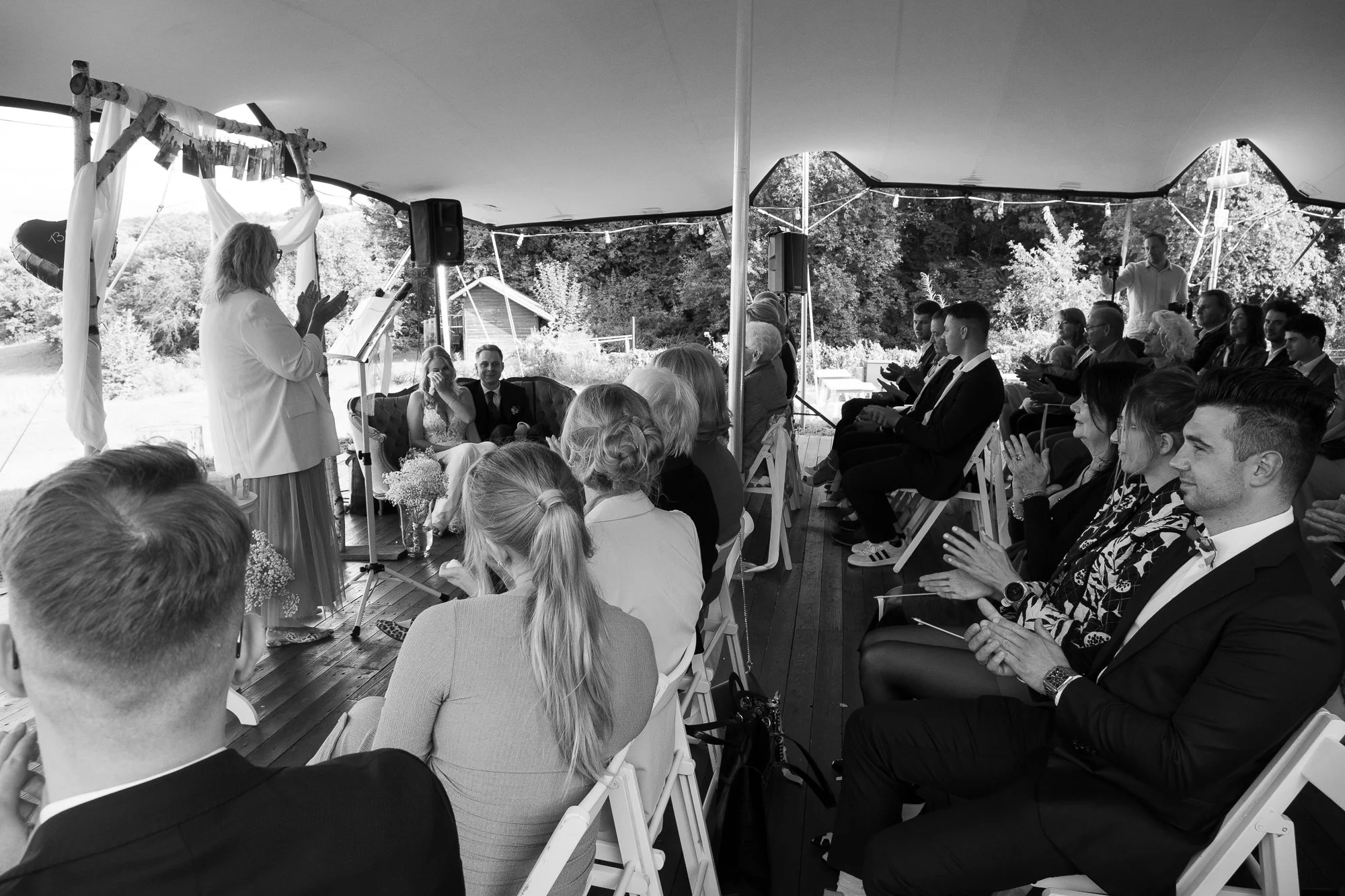 Hochzeit unter einem Zelt im Freien mit Hochzeitsgästen, die zum Standesamt, sehen zu.