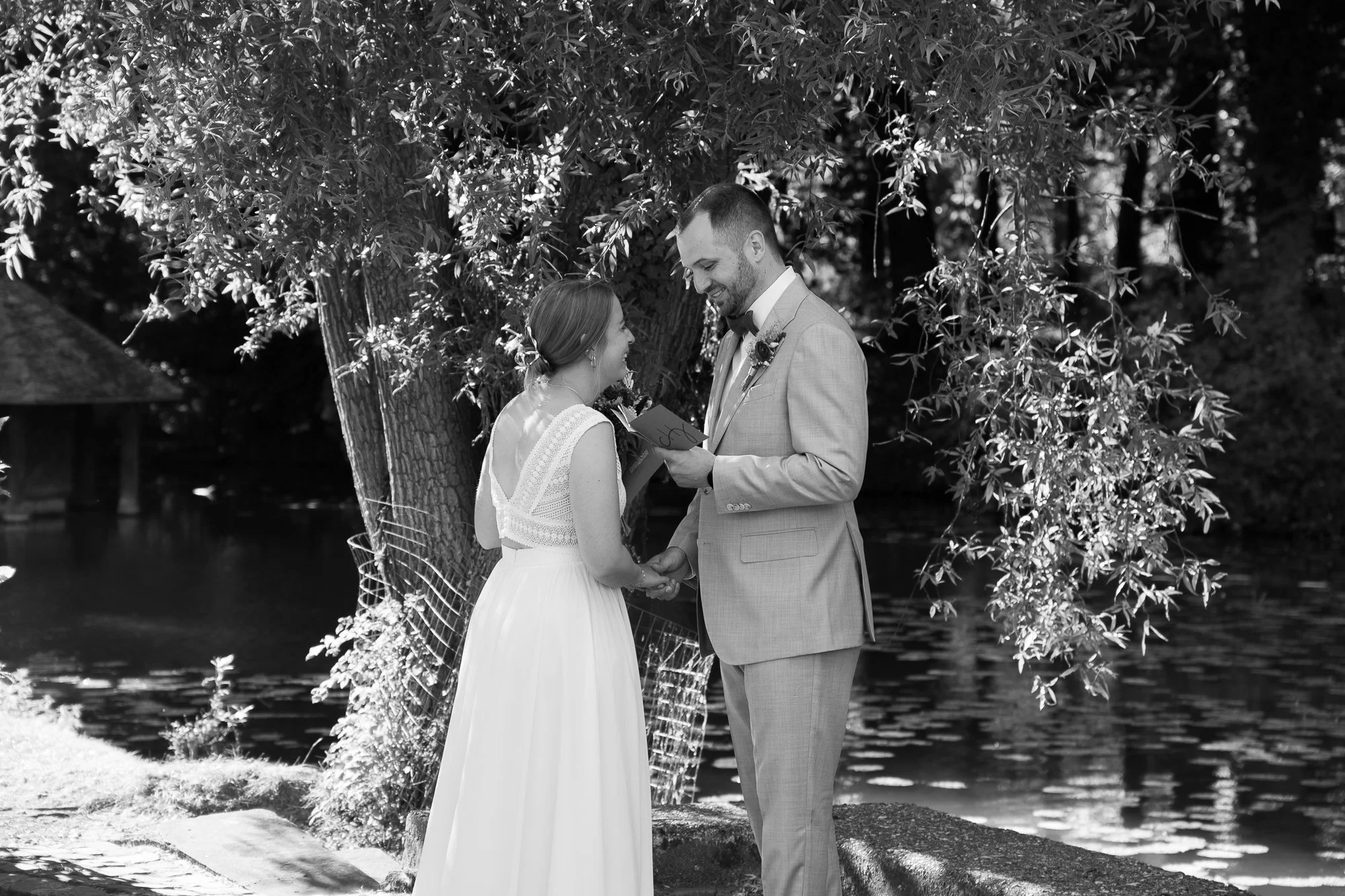 Ein Brautpaar bei einer Heiratszeremonie im Freien unter einem Baum, beim Austausch der Ehegelübde, im Schwarz-Weiß-Foto