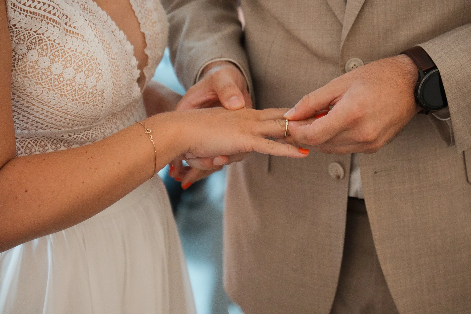 Nahaufnahme eines Hochzeitsrings, der beim Heiratsversprechen zwischen einem Paar ausgetauscht wird, wobei der Schwerpunkt auf den Händen und dem Ring liegt.