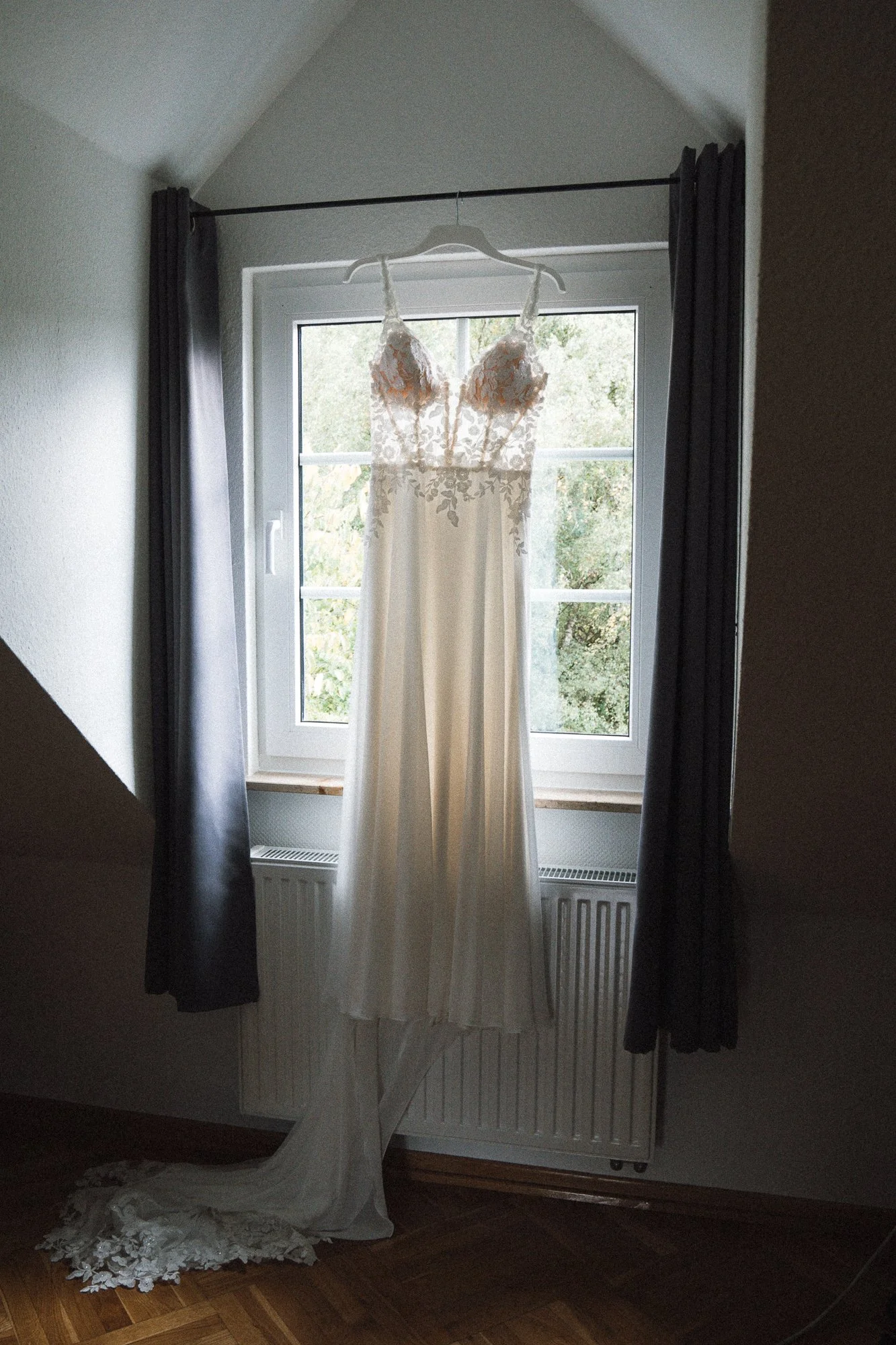 Brautkleid hängt an einem Kleiderbügel vor einem Fenster