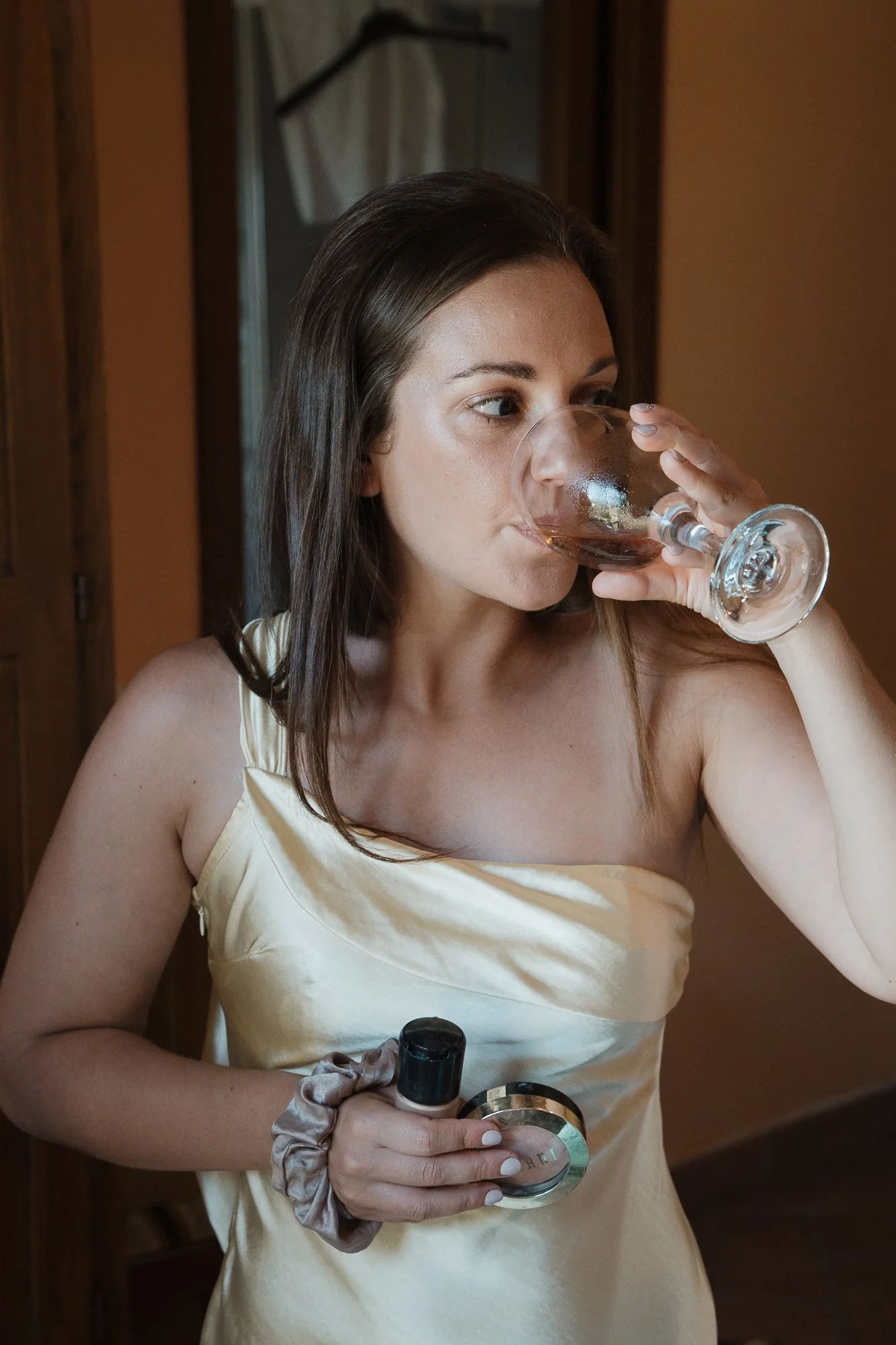 Junge Frau trinkt Rotwein aus einem Weinglas in einem Raum mit Holzdekoration.