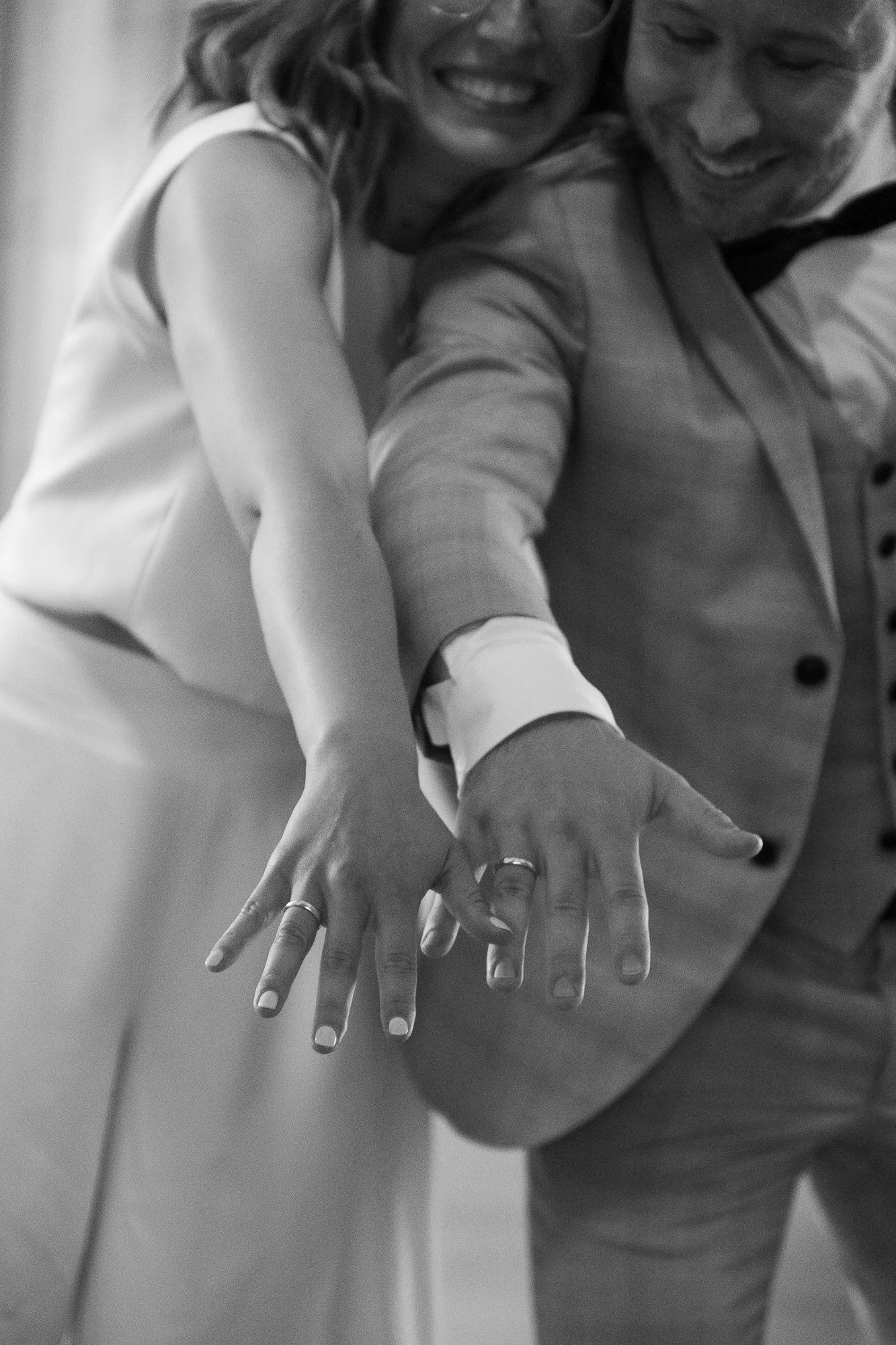 Zwei Menschen, wahrscheinlich ein Paar, zeigen ihre Eheringe auf den Händen bei einer Hochzeit oder Feier.