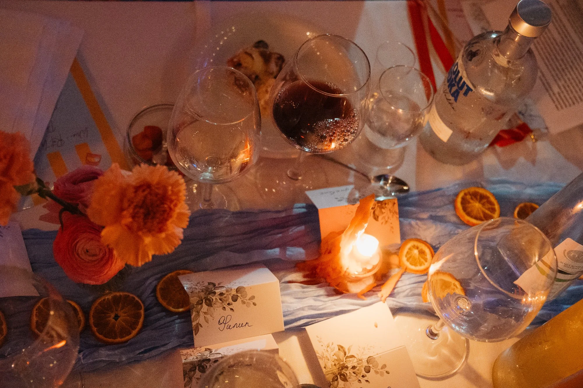 Tischdeko mit Blumen, Kerzen, Gläsern, Orangen und Wasserflasche bei Dinner