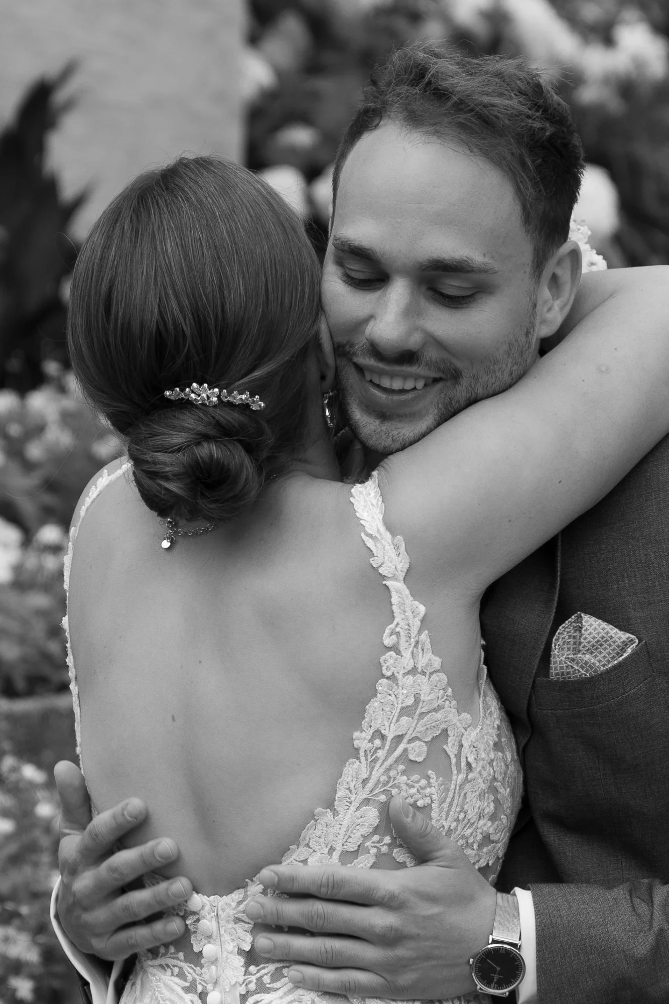 Ein Brautpaar umarmt sich bei ihrer Hochzeit, Schwarz-Weiß-Foto, romantische Atmosphäre, elegante Kleidung