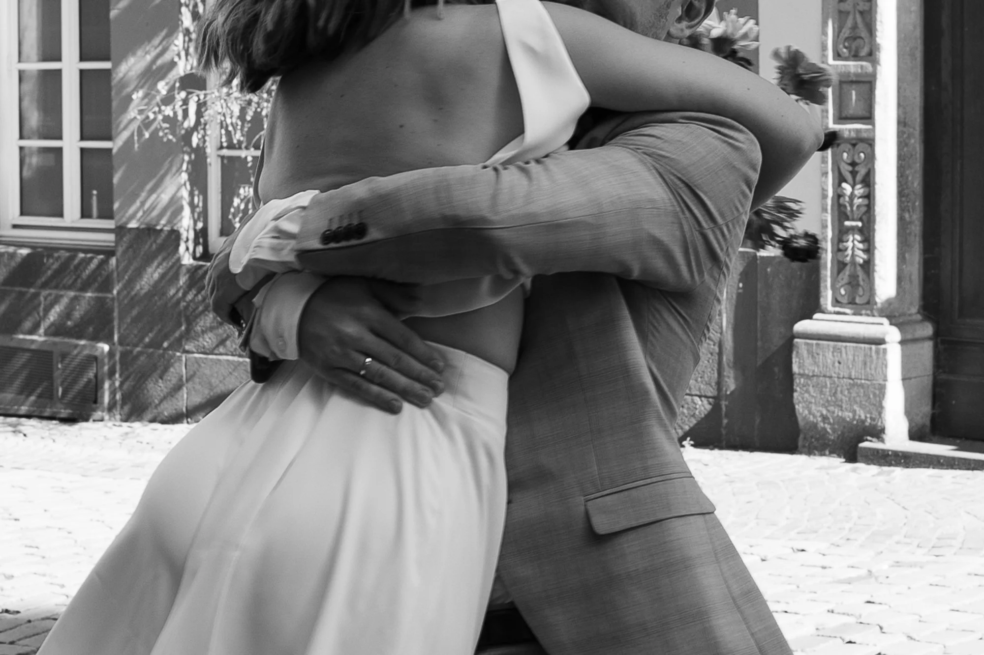 Ein Paar beim Tanzen im Freien, in Schwarz-Weiß-Fotografie aufgenommen, Nahaufnahme, Fokus auf ihre Haltung und Kleidung.