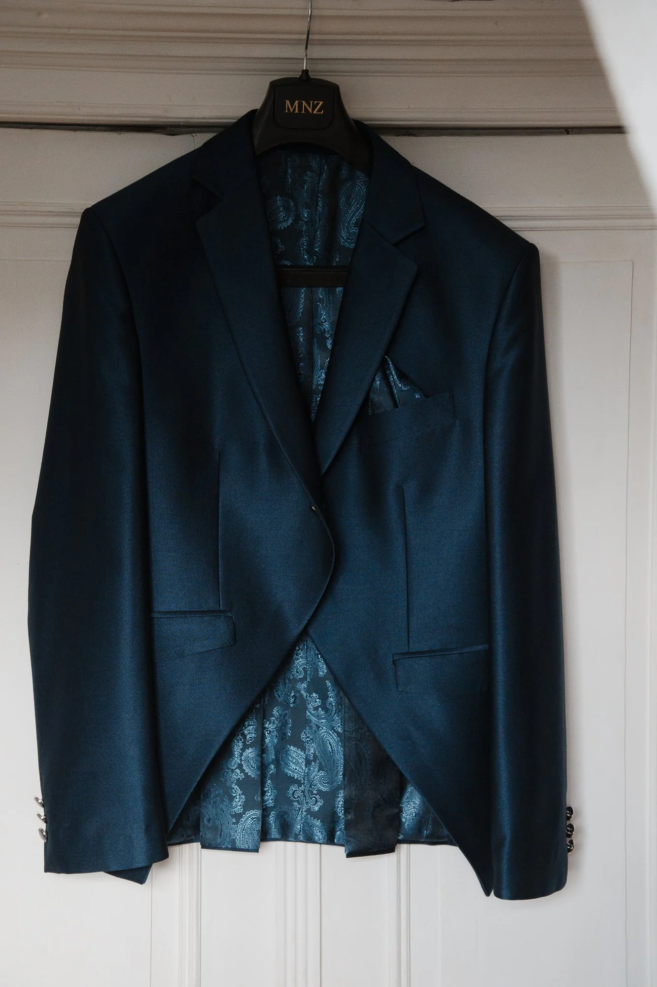 Dunkelblauer Abendanzug auf einem Kleiderbügel im Raum.