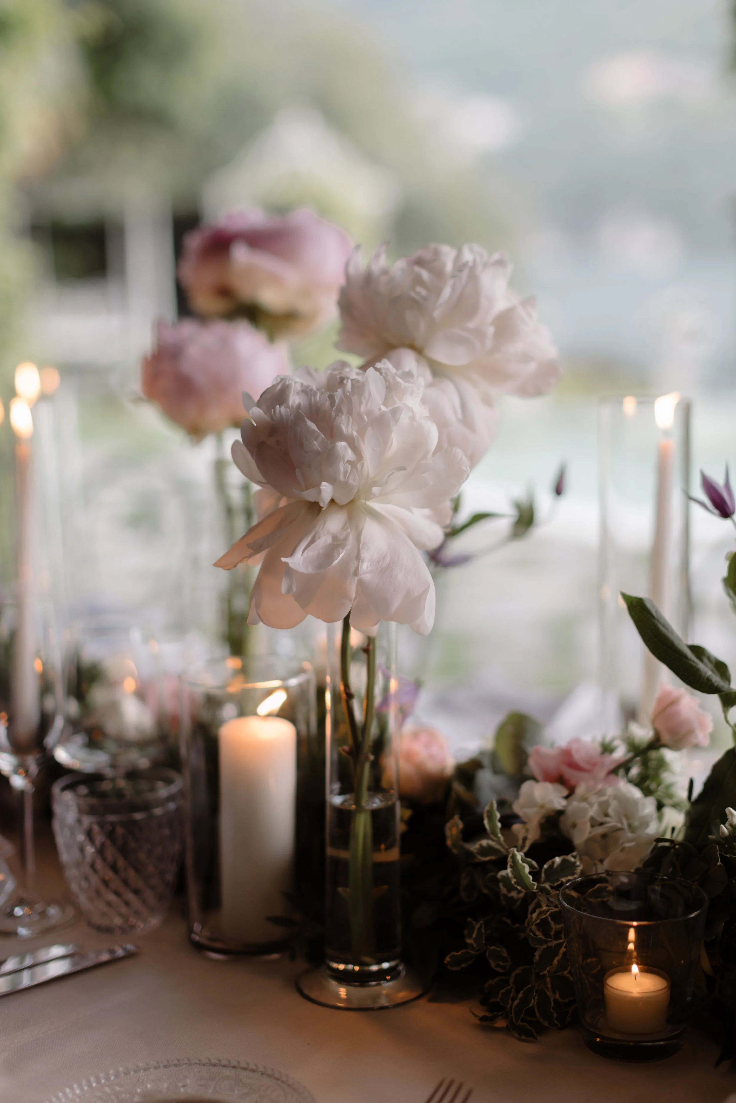 A white flower and green foliage arranged on a white chair at an outdoor event.
