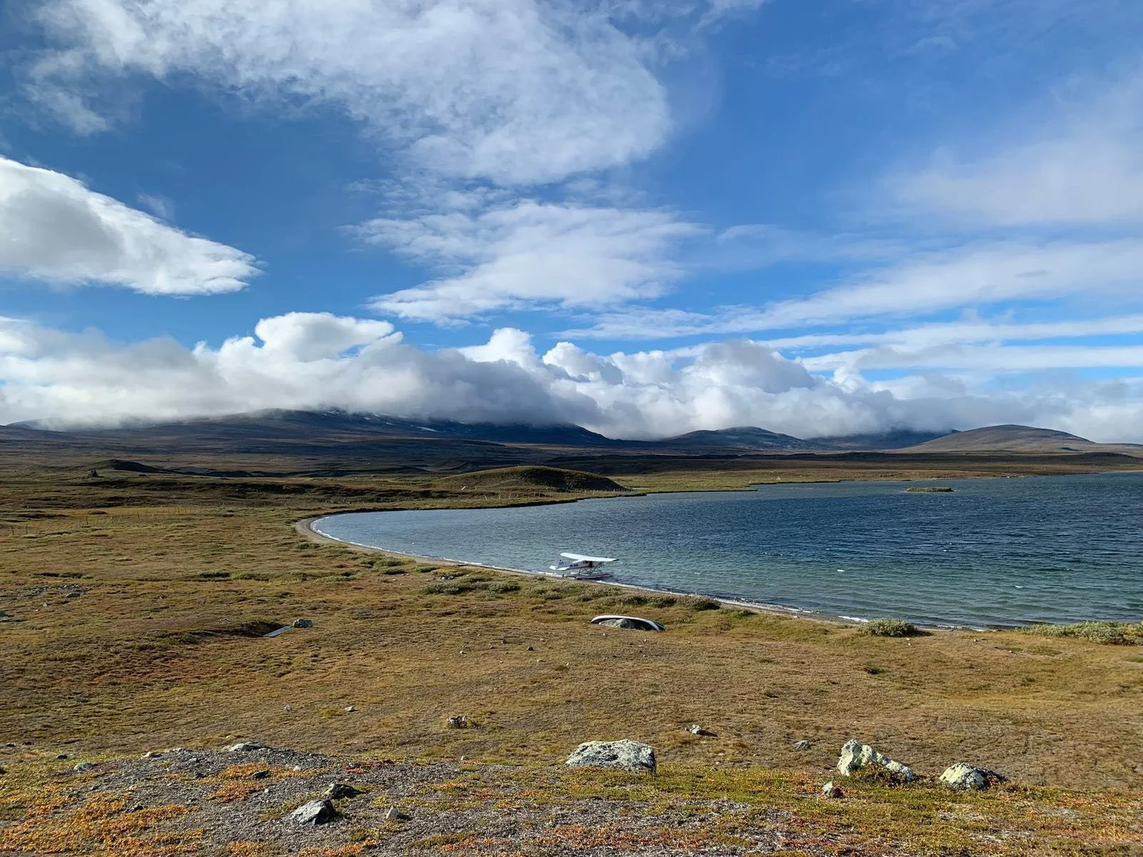 Polar-Lento Oy:n vesitasokone rantautuneena kirkkaan järven rantaan, taustalla sininen taivas ja tunturi.