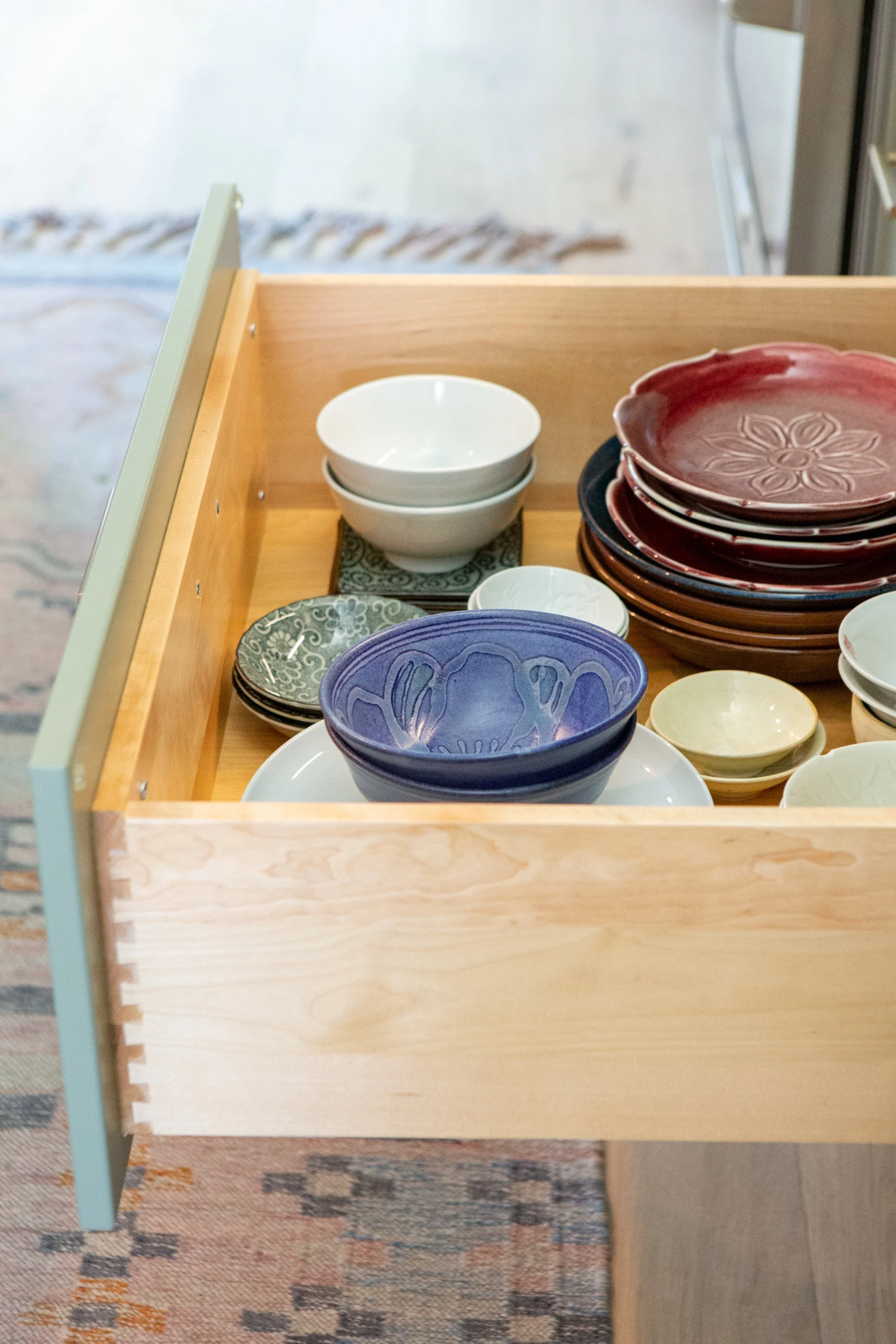 Stacks of colorful ceramic bowls on a wooden display shelf in a store.