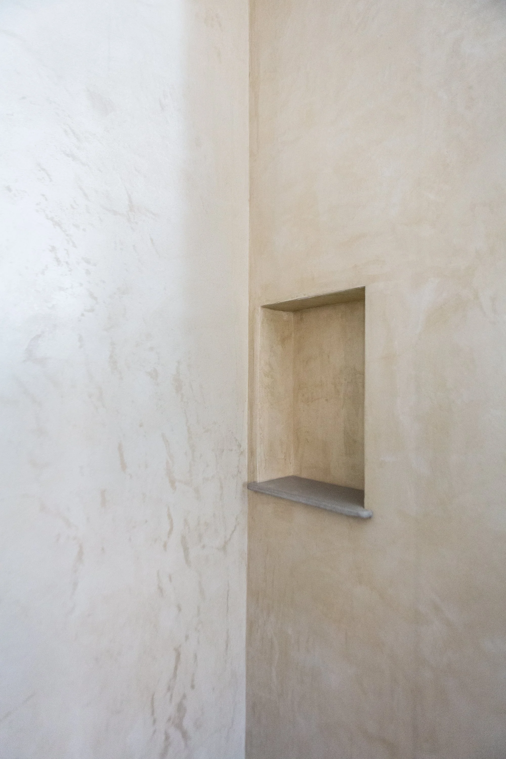 Interior wall with a small recessed shelf and a marble ledge, painted in beige tones.