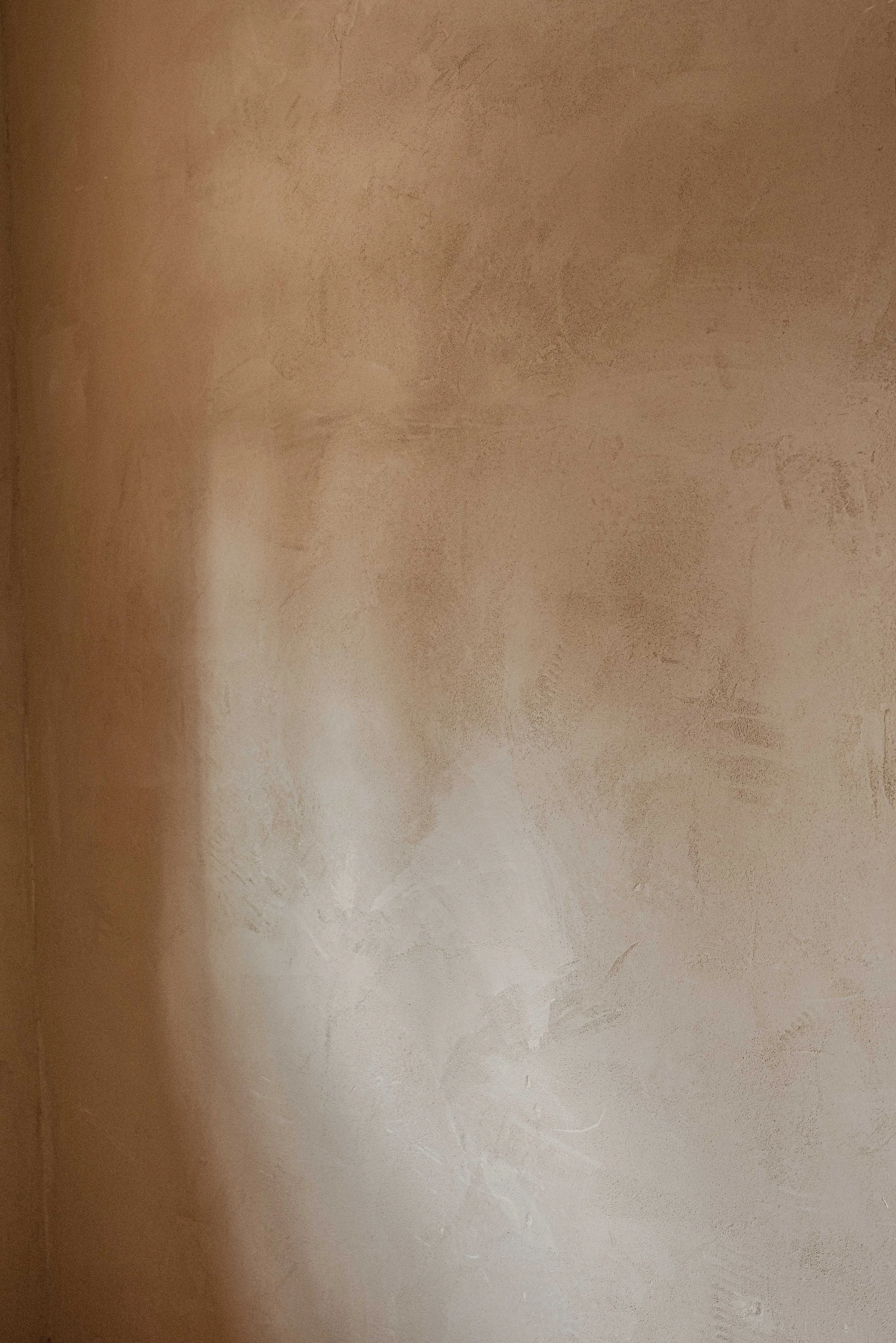 Close-up of a textured beige wall with uneven surface and color variations.