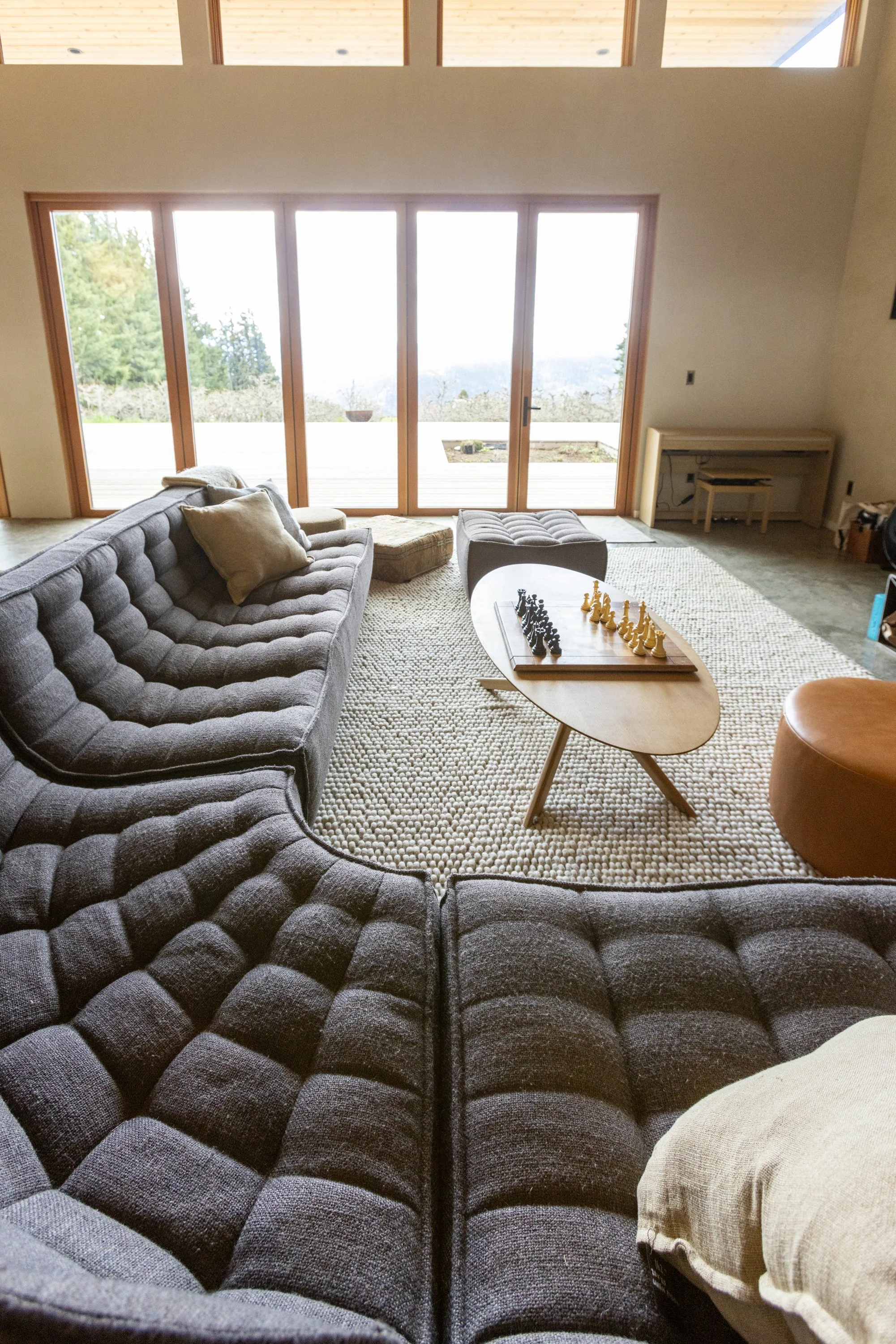 Living room with large glass sliding doors showing an outdoor deck and a scenic view of trees and mountains in the background.