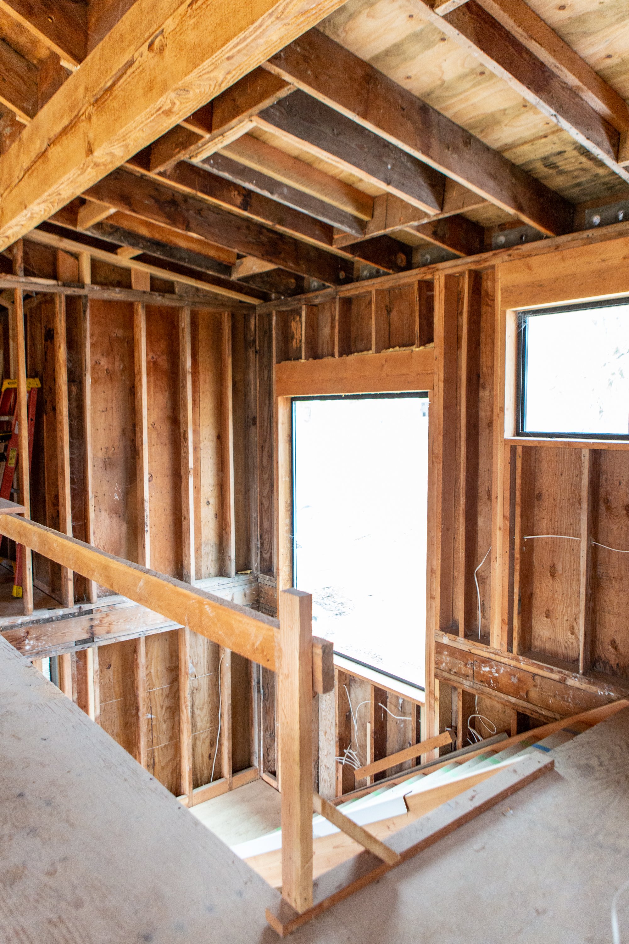 Interior view of a house under construction with exposed wooden framing and unfinished walls and ceiling.