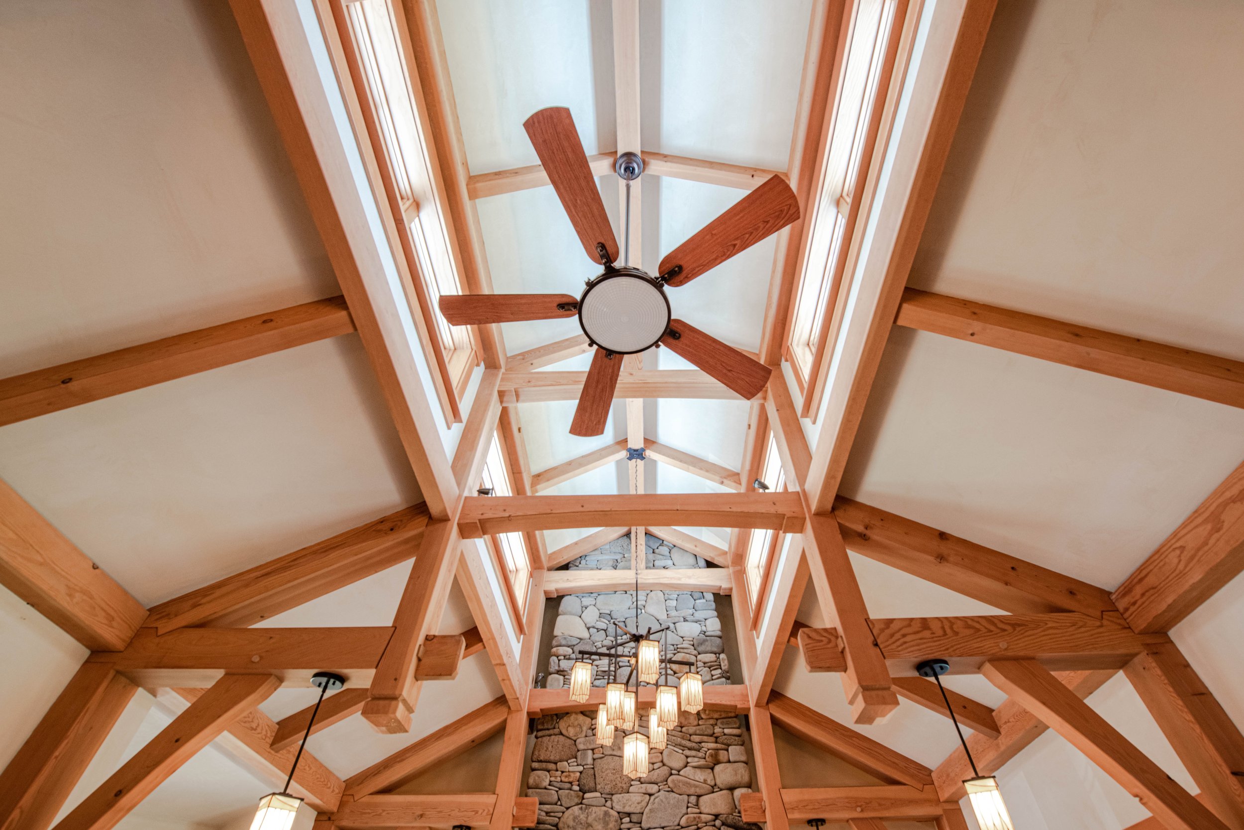 Ceiling view of a rustic interior with exposed wooden beams and a ceiling fan.