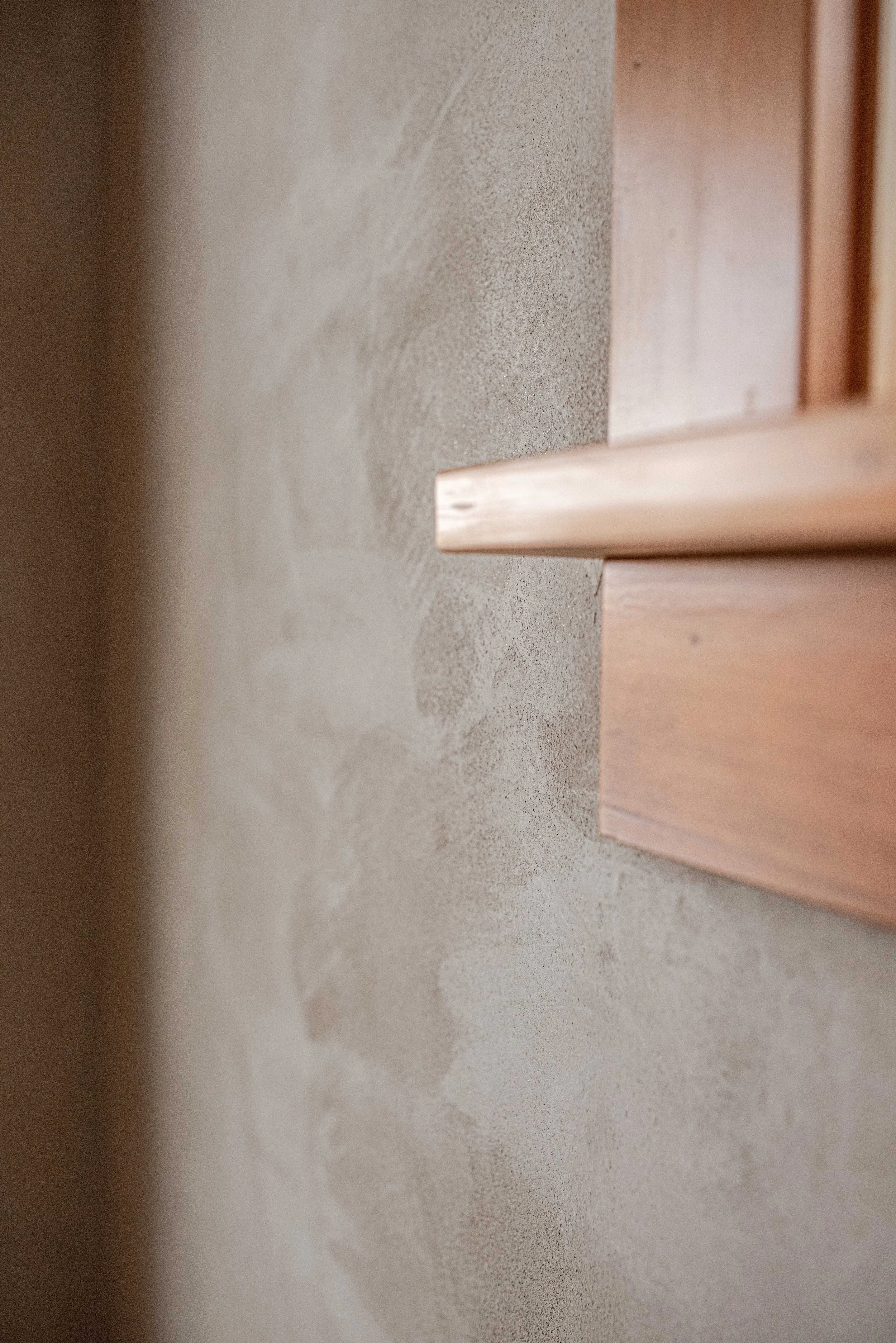 Close-up of light-colored wooden furniture with textured wall in background.