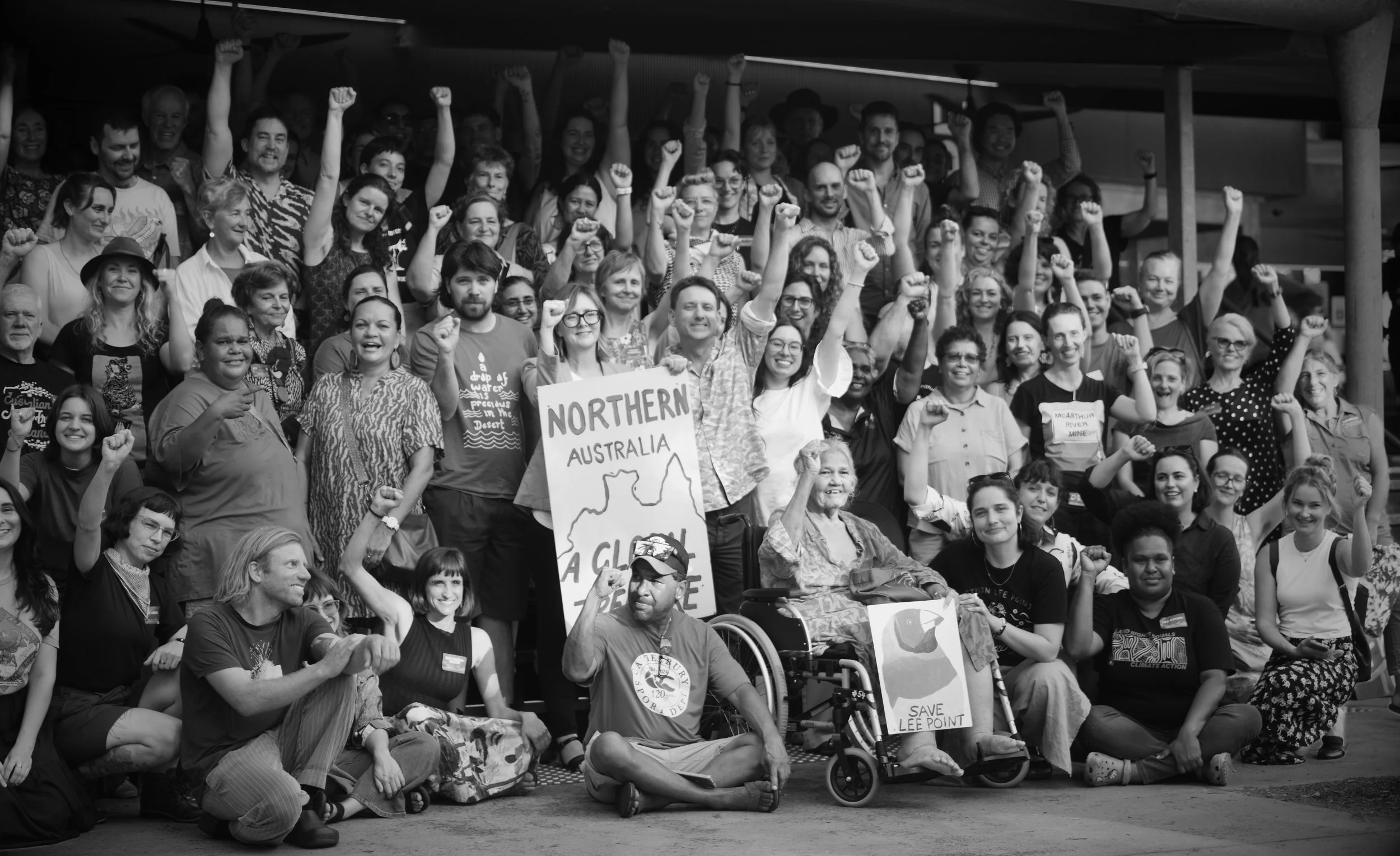 Group photo of diverse people gathered together, many raising fists, with signs advocating for Northern Australia and environmental conservation.