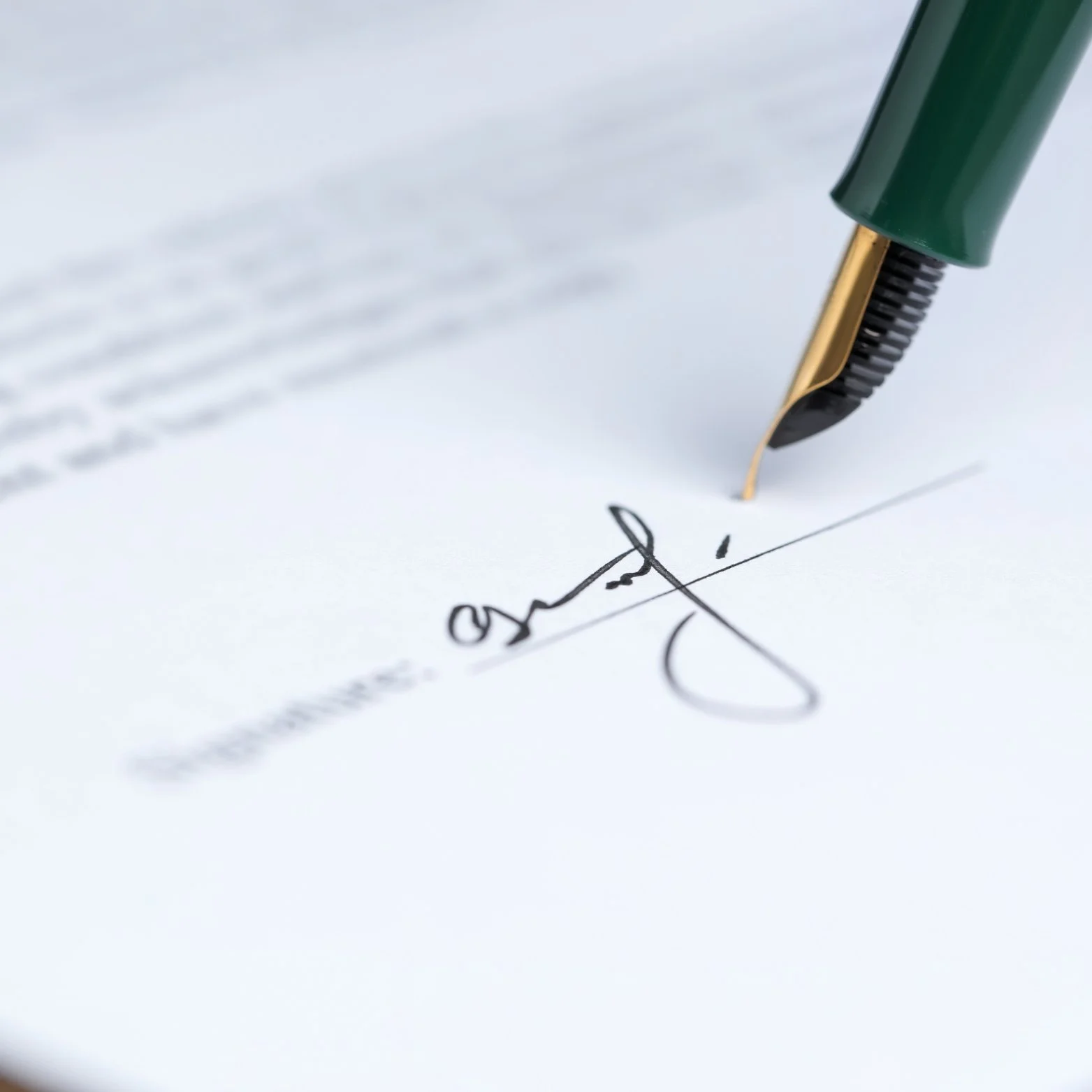 Close-up of a green and gold fountain pen signing a document with black ink.