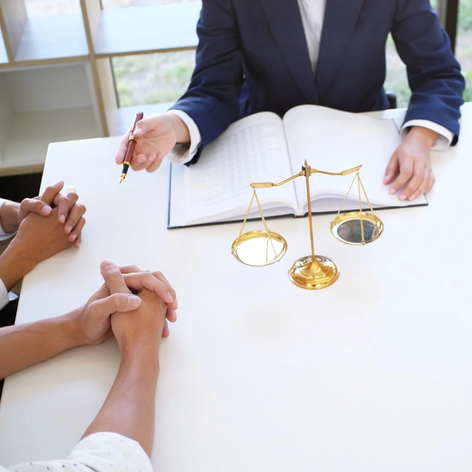 A legal consultation with a lawyer and a client sitting at a table, with a scale of justice in the center.