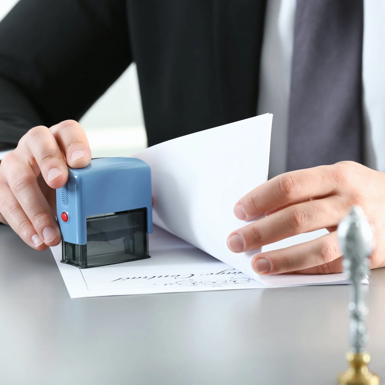 Person stamping a document with a blue sealing stamp.