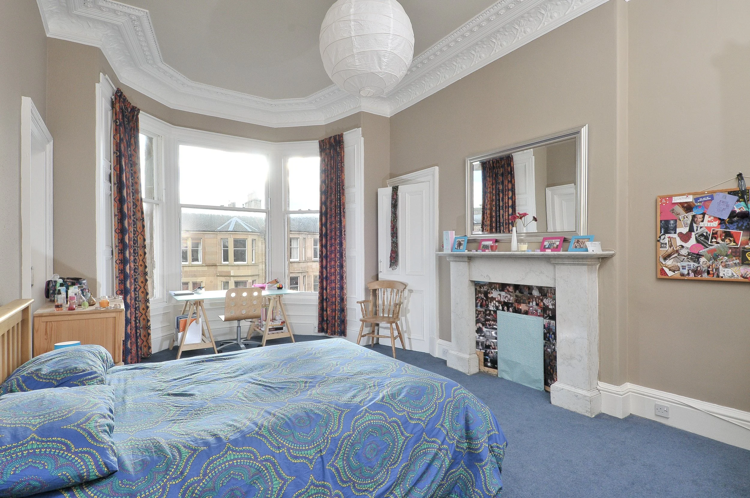Scenic landscape of a mountainous region with a lake, green hills in the foreground, and cloudy sky overhead.