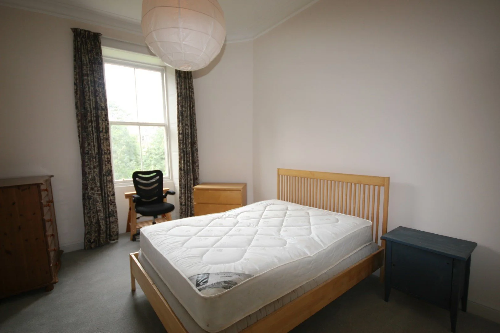 A modern wooden house with large glass windows set against a mountainous landscape, with some people visible through the window.