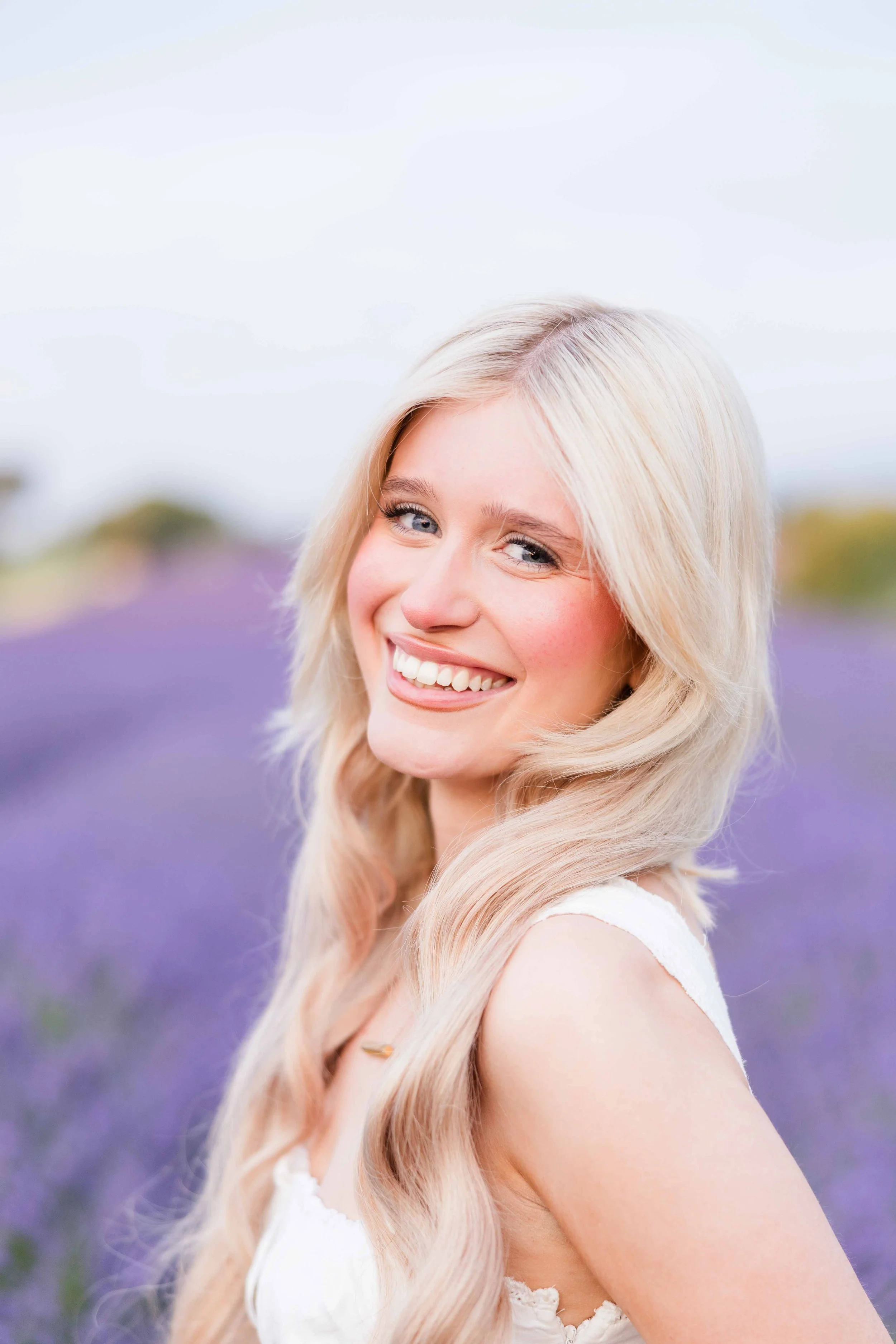 Portrait lumineux d'une future mariée blonde souriante en robe blanche et chapeau, shooting photo Provence lavandes