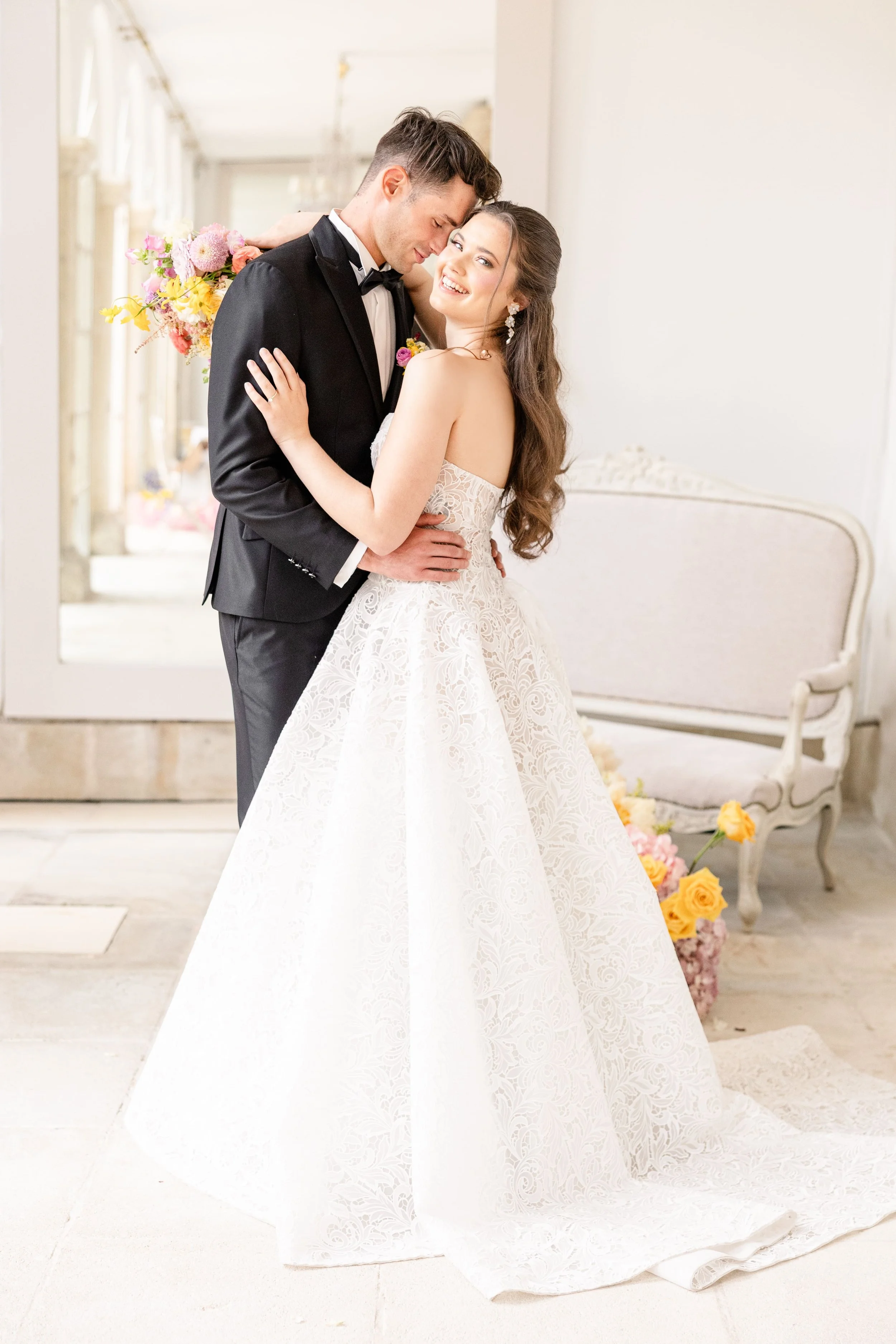 Photo de couple des mariés s'enlaçant dans la galerie lumineuse d'un château, ambiance chic et raffinée pour un mariage en Provence.