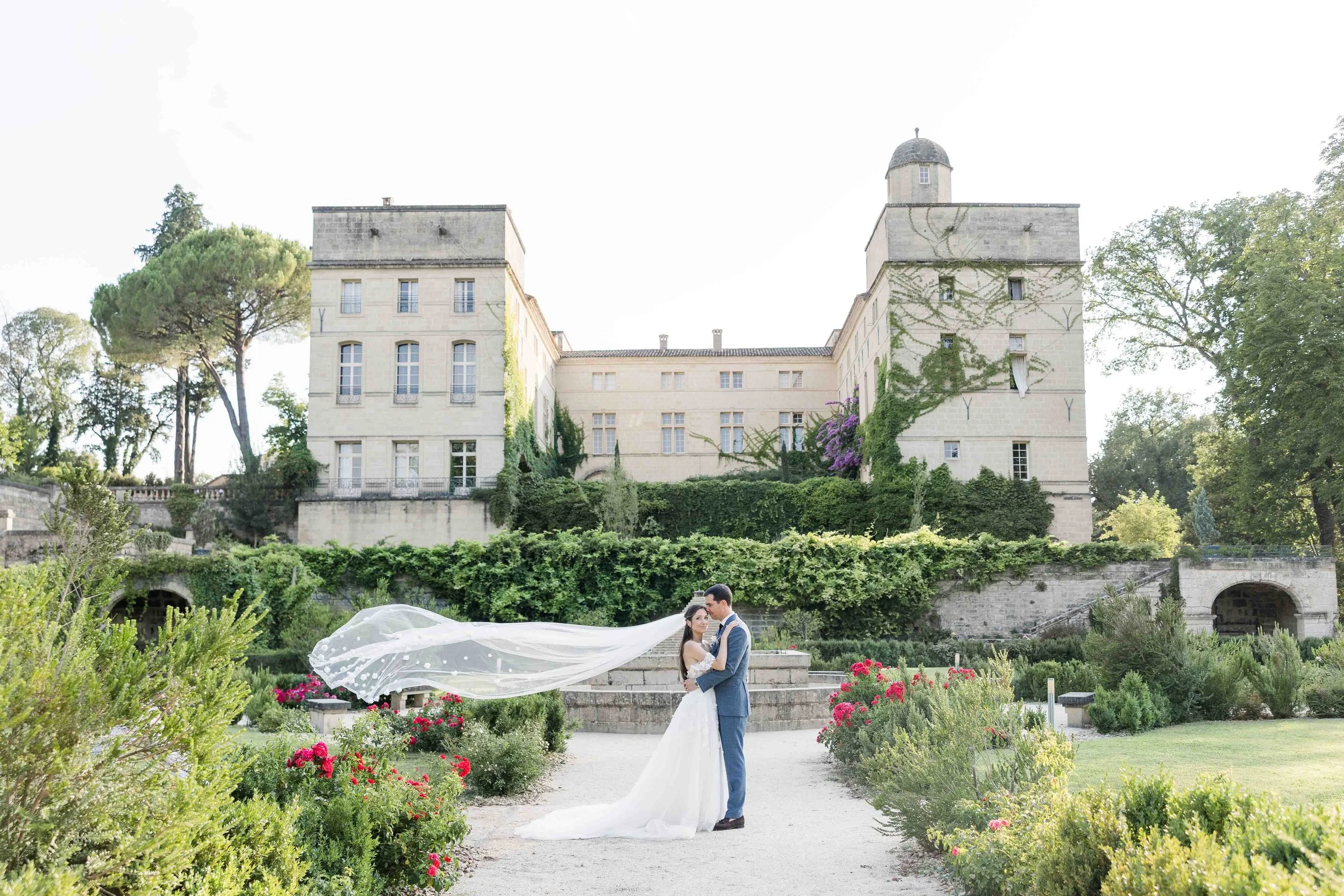 portrait de marié avec le voile flottant devant leur chateau en provence