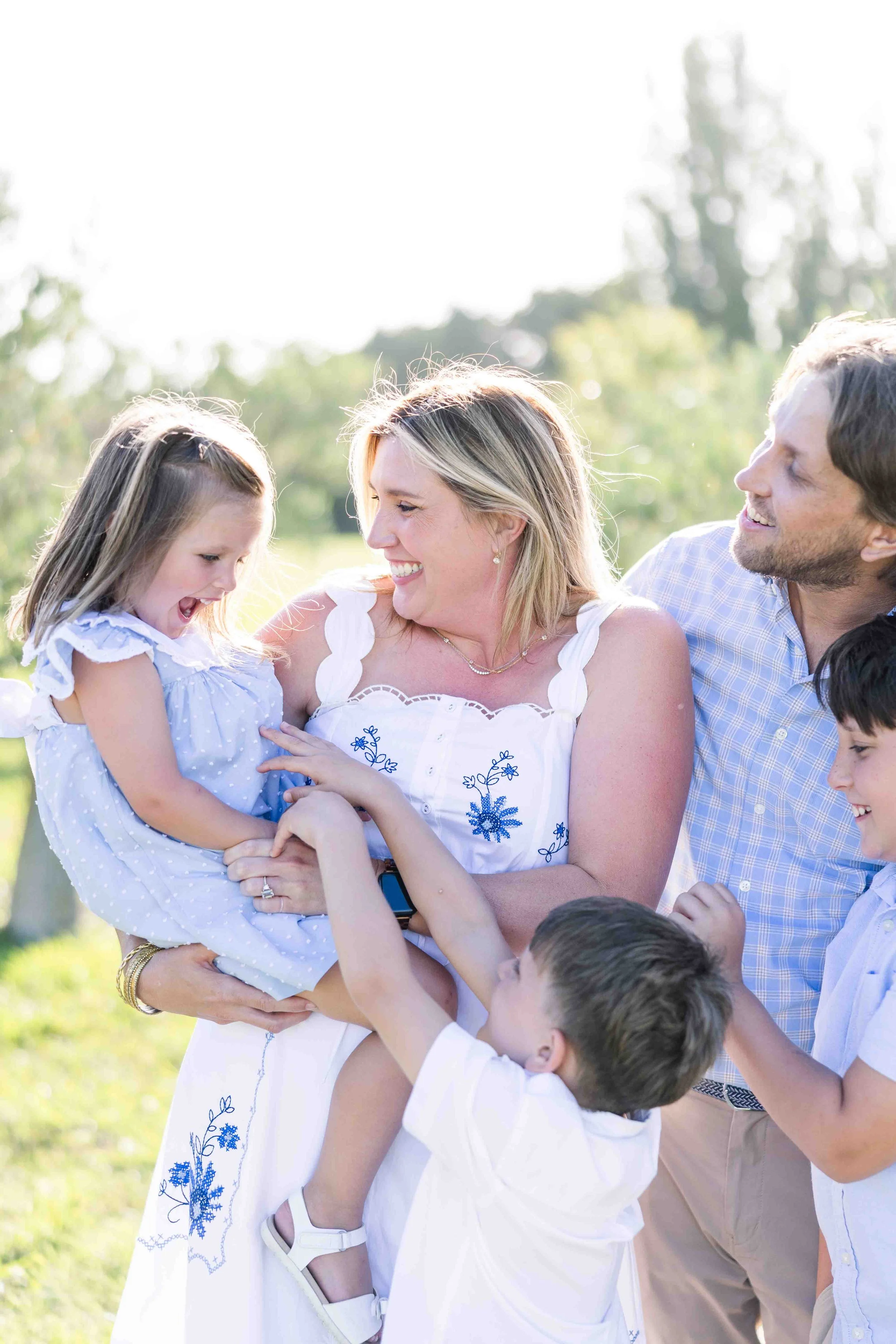 Moment de jeu et de rires spontanés entre des parents et leurs jeunes enfants en extérieur dans un domaine en Provence.