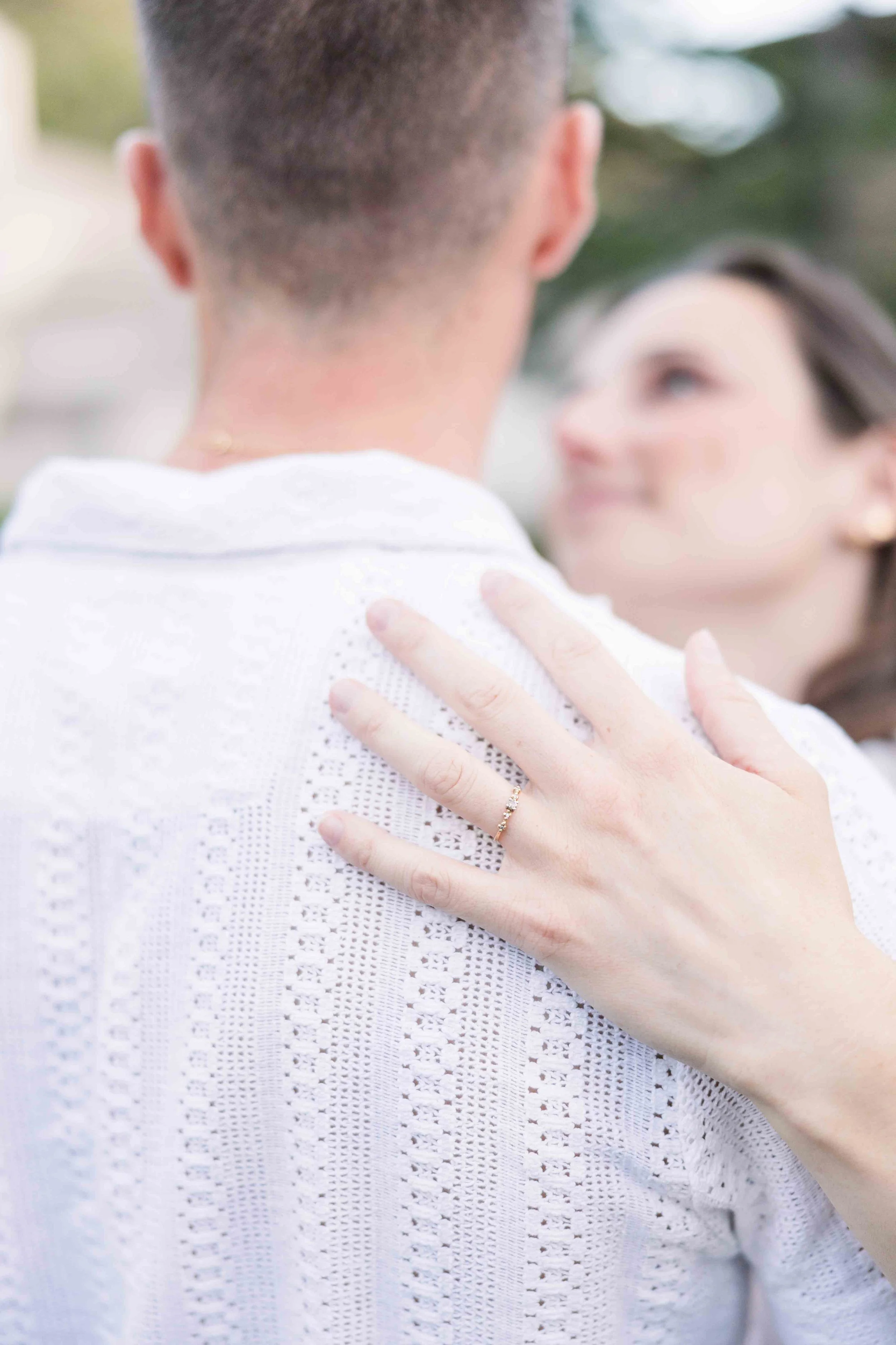 Gros plan sur la main d'une femme posée sur l'épaule de son fiancé, mettant en valeur la bague d'engagement lors d'un shooting à Sénanque.