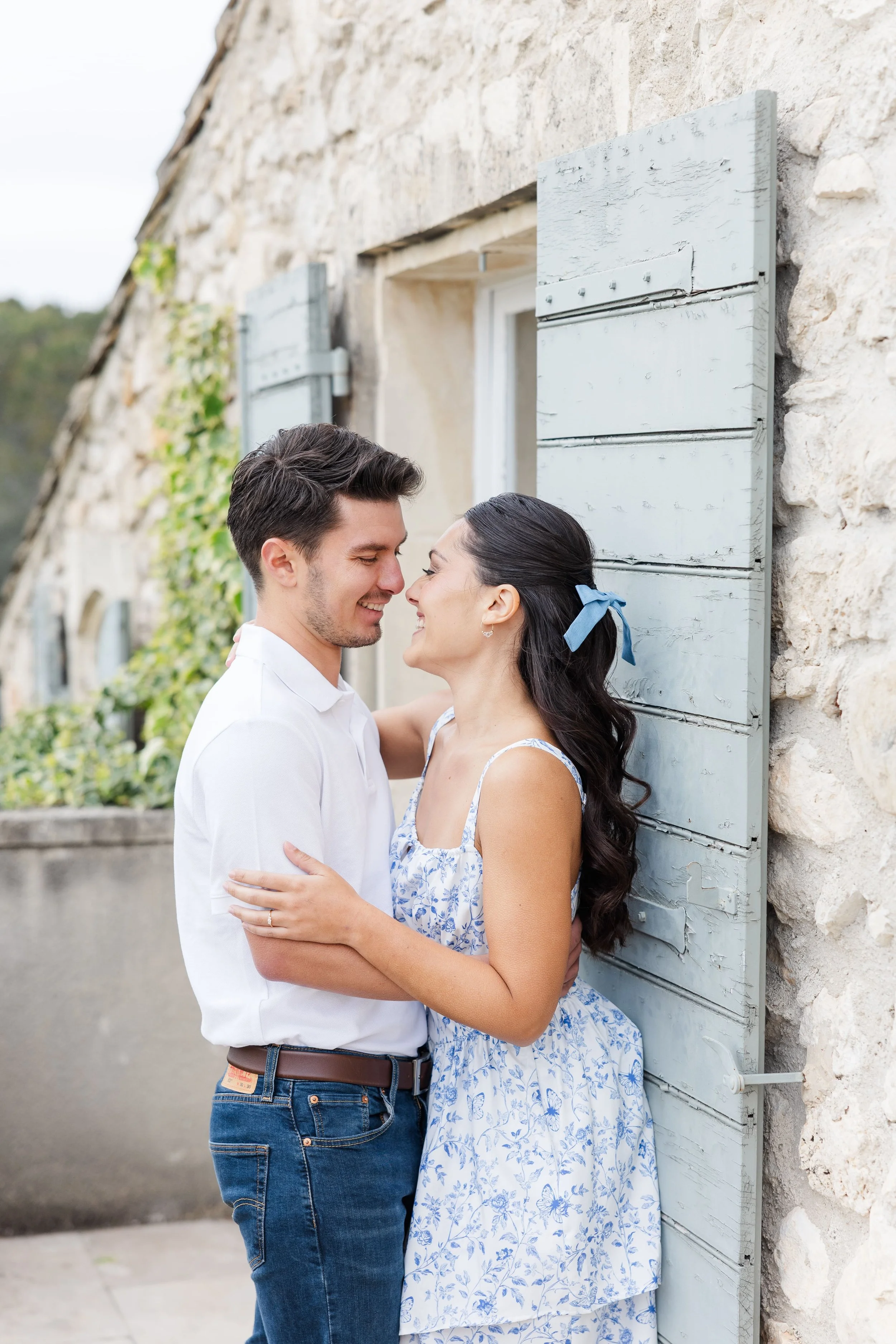 Un plan moyen du couple s'embrassant sur une allée du parc devant la bastide du Mas de La Rose dans les Alpilles.