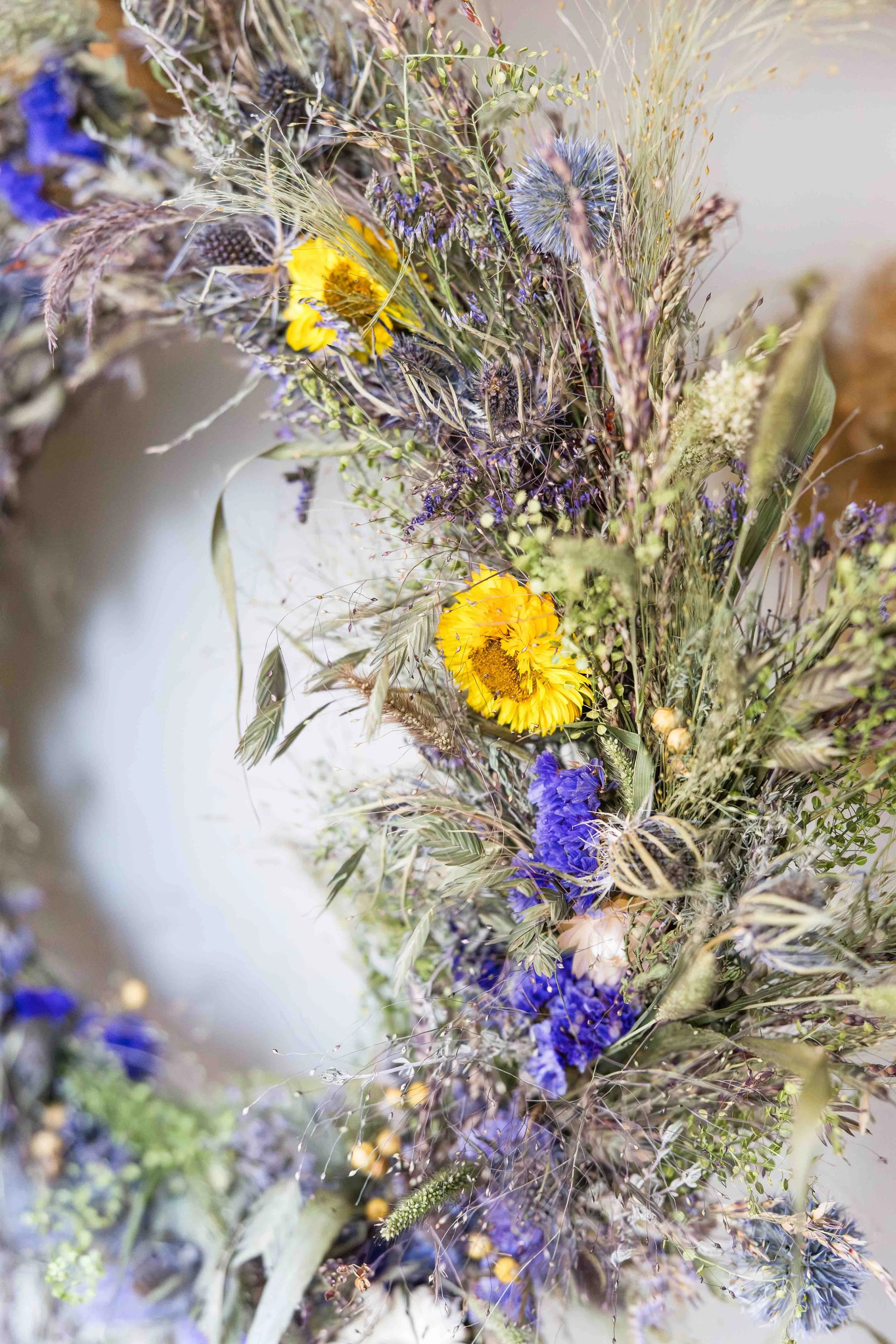 Couronne de fleurs séchées artisanale aux teintes violettes et jaunes réalisée par un fleuriste en Provence