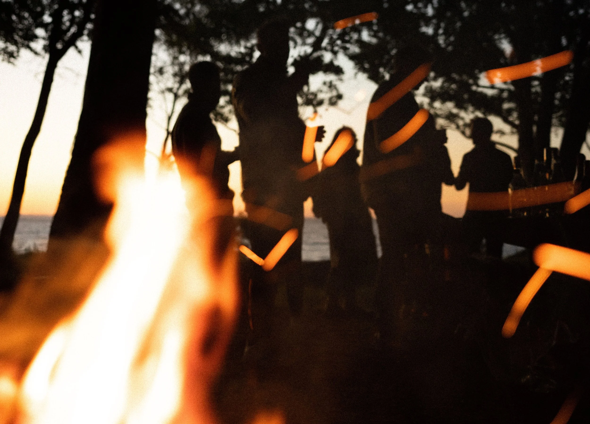 Silhuetter af mennesker ved grill ved aftenstid, med himlen i baggrunden