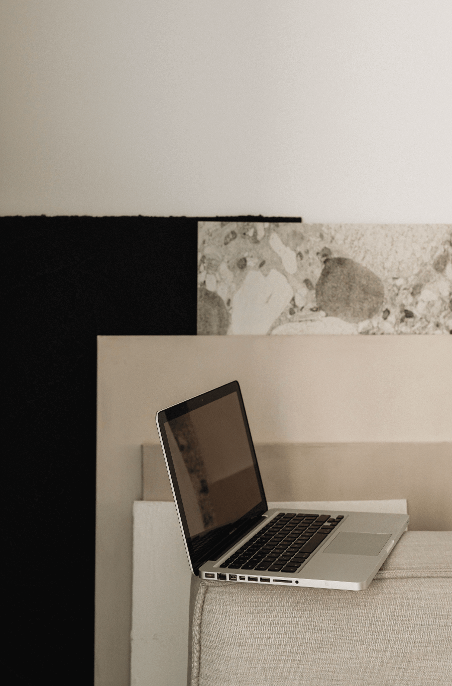 Ein offener Laptop steht auf einer beige Couch im Raum, mit einer Wand im Hintergrund, die teilweise mit schwarzem, weißem und gemustertem Design gestaltet ist.