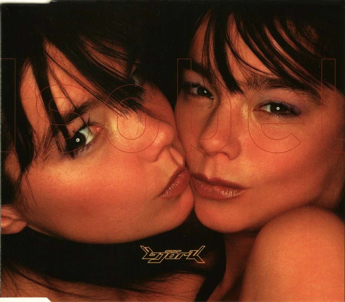 Deux femmes avec des maquillage irisé et des cheveux noirs se rapprochant l'une de l'autre, regardant l'objectif.