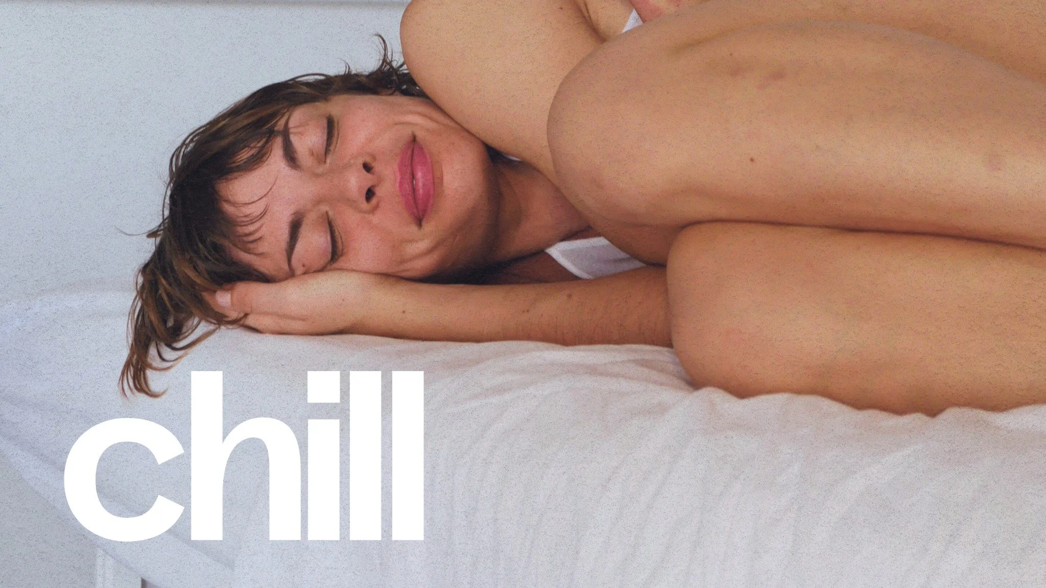Une femme nue allongée sur un lit blanc, avec les yeux fermés et un sourire détendu, tenant sa tête avec sa main. Le mot 'chill' en texte blanc en bas à gauche.