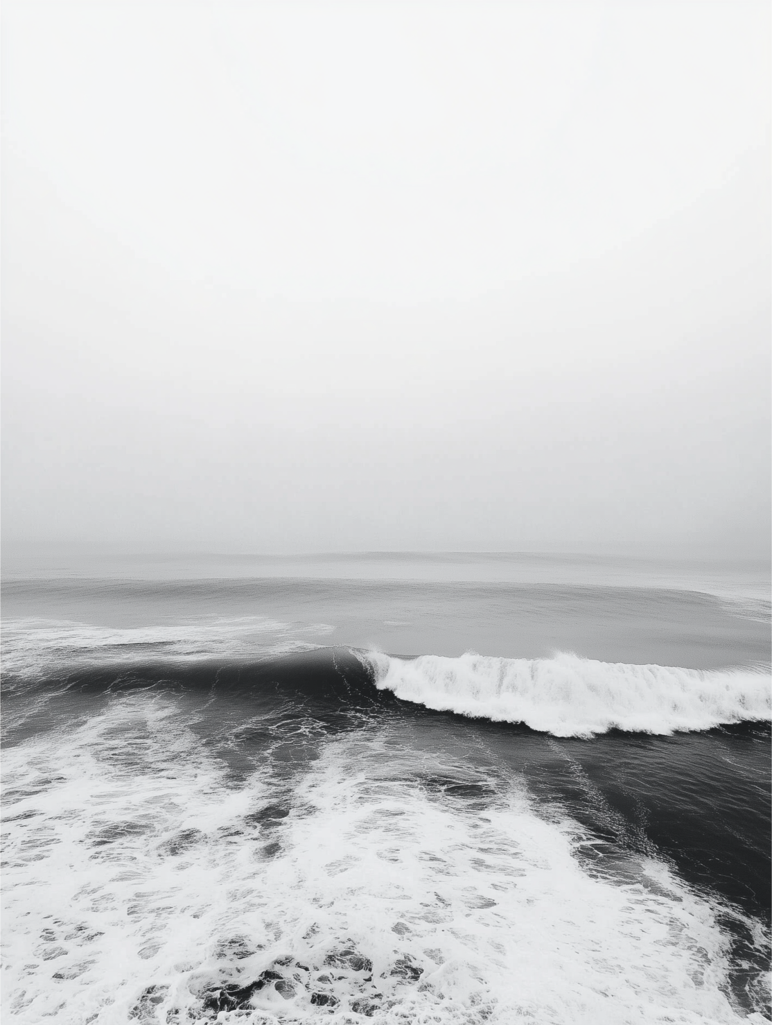 Black and white photo of ocean waves with clouds above