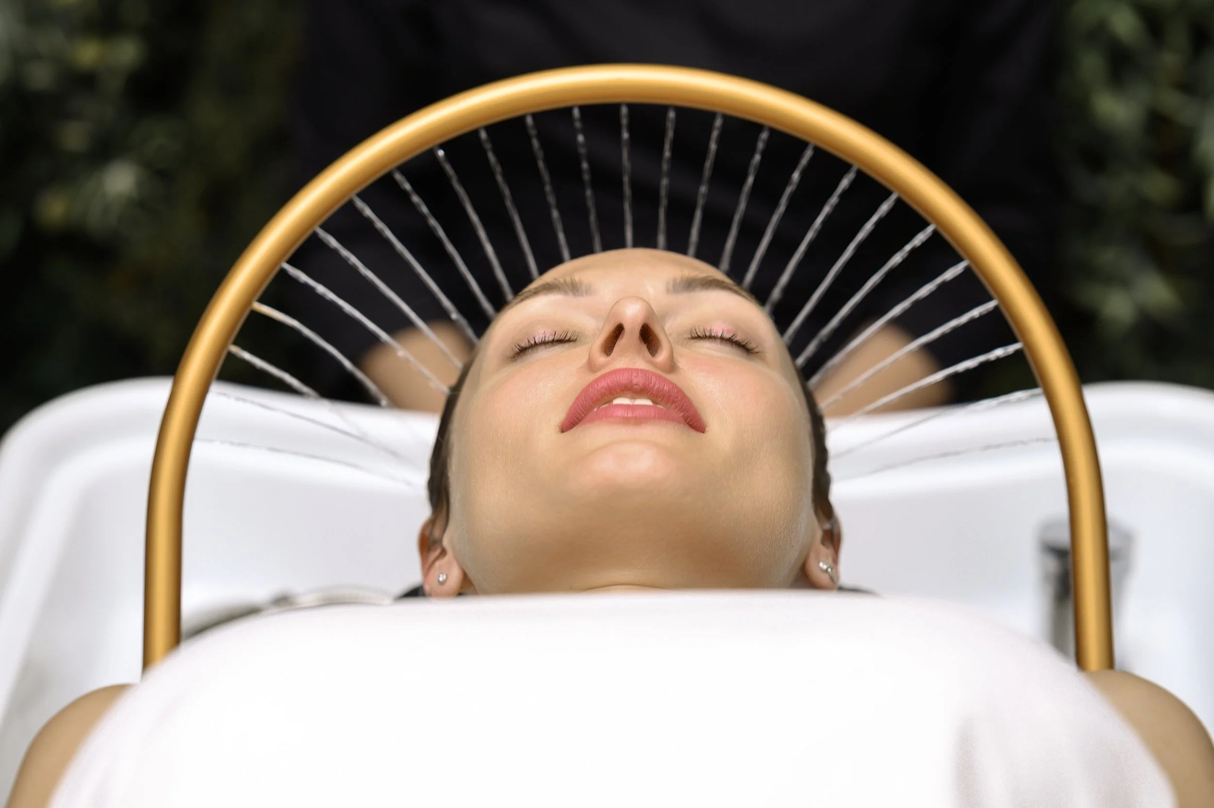 Femme allongée sur une table de spa, avec une tête reposant sur une serviette blanche, yeux fermés, ambiance de relaxation.