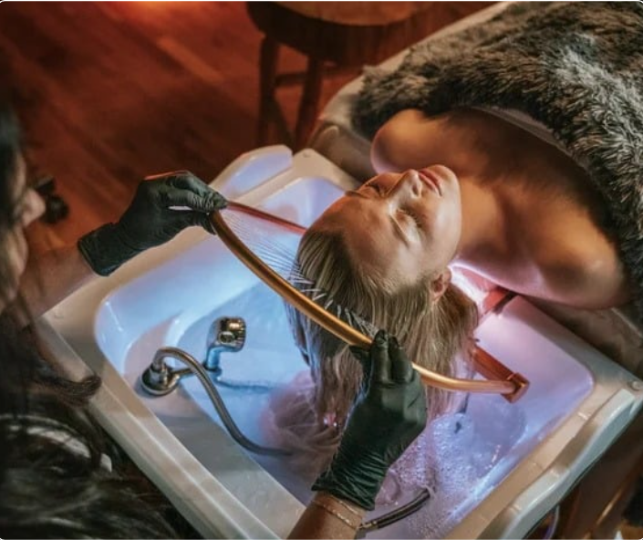Une femme subissant un soin head spa, allongée avec les yeux fermés.