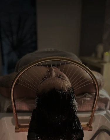 Une femme reçoit un traitement de cheveux ou de cuir chevelu sous une lumière violette dans un environnement de spa ou de salon de beauté.