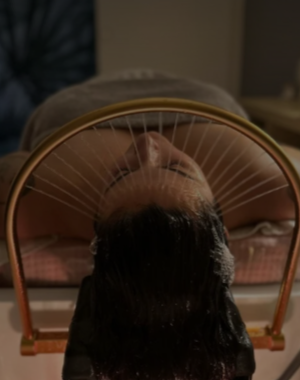 Une personne repose sur le dos, en train de se faire faire un soin head spa.