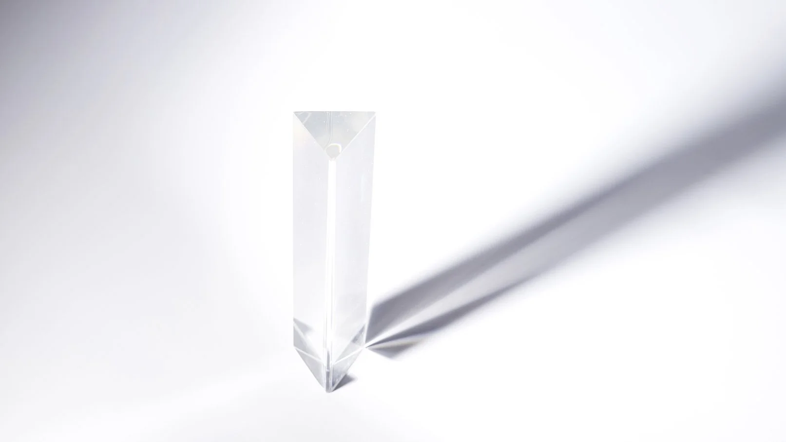 Un cristal rectangulaire transparent avec une ombre allongée sur un fond blanc.