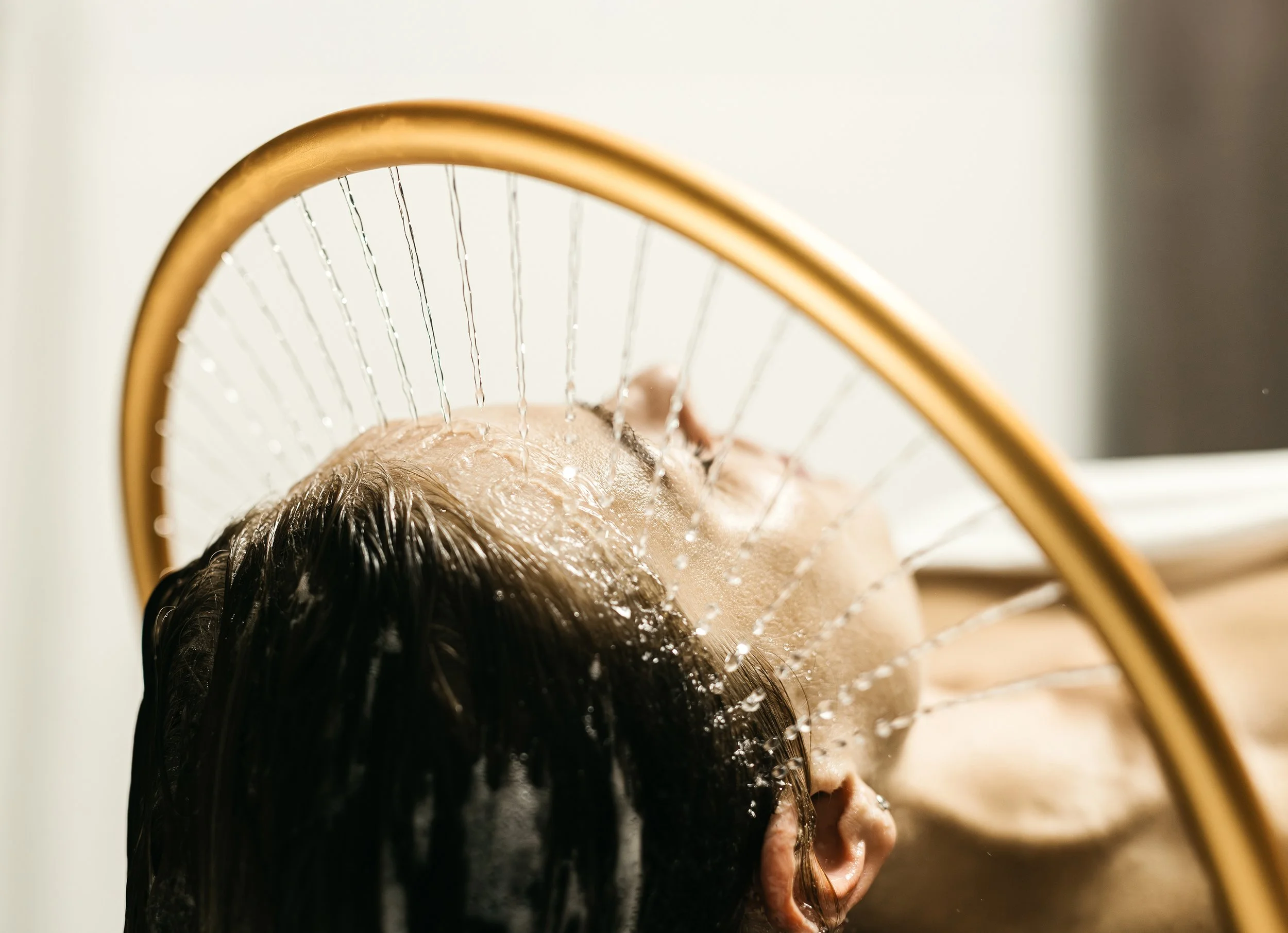 Une femme subissant un soin head spa, allongée avec les yeux fermés.