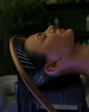 Une femme subissant un soin head spa, allongée avec les yeux fermés.